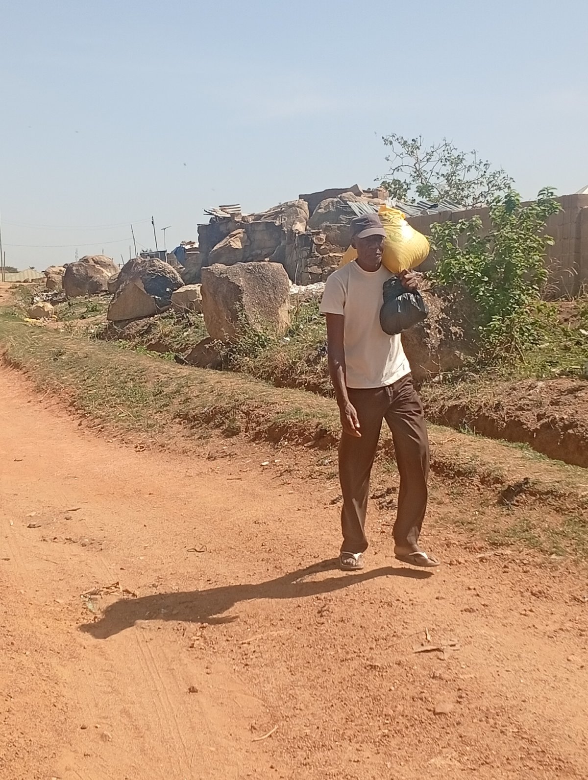 Man carries large sack while walking dirt road in Nigeria