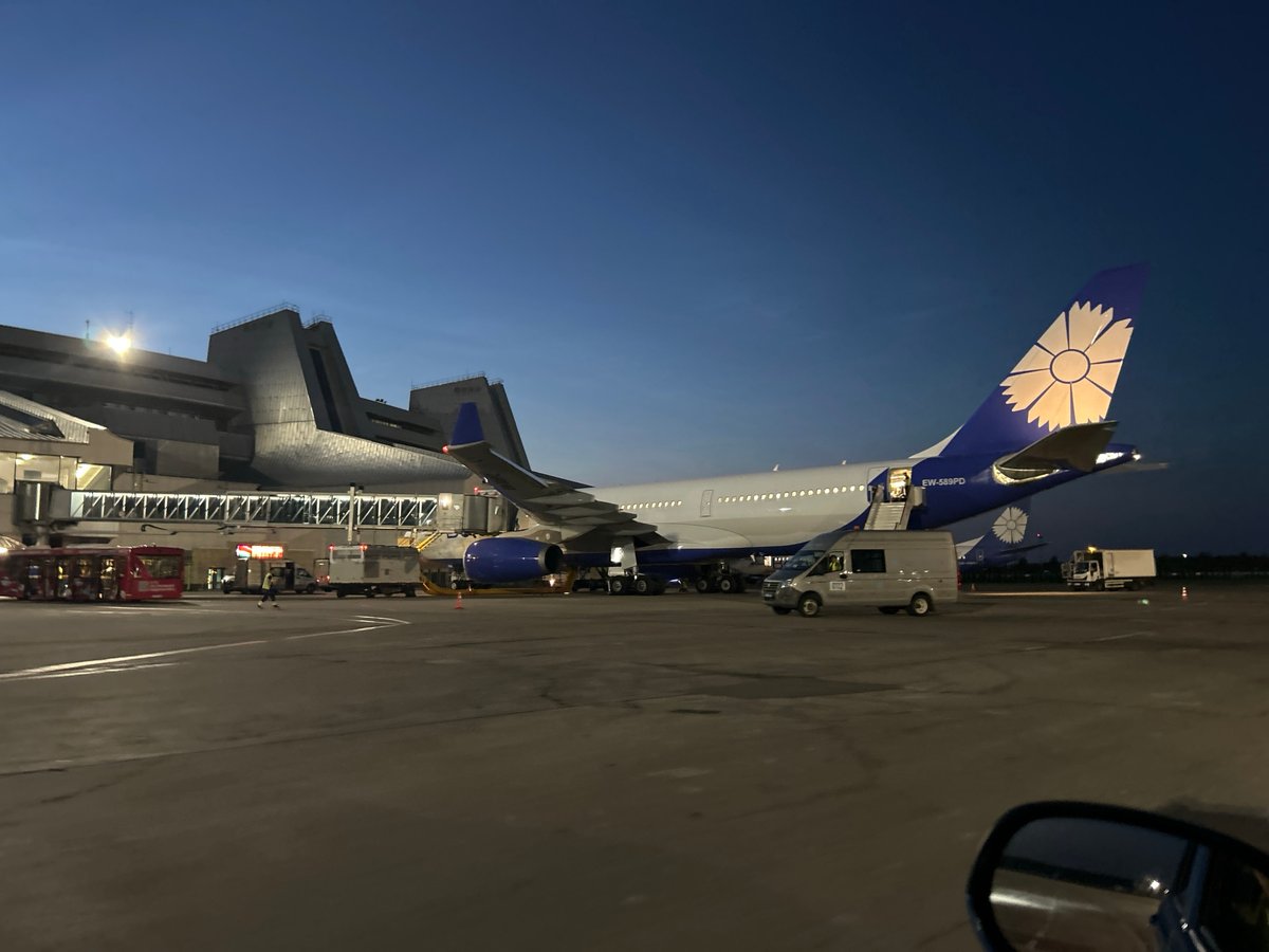 Blue and white wide-body jet parked at Minsk Airport at dusk
