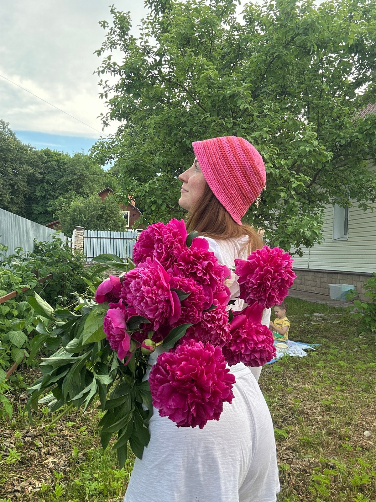Woman poses with pink peonies in Nizhny Novgorod backyard photoshoot