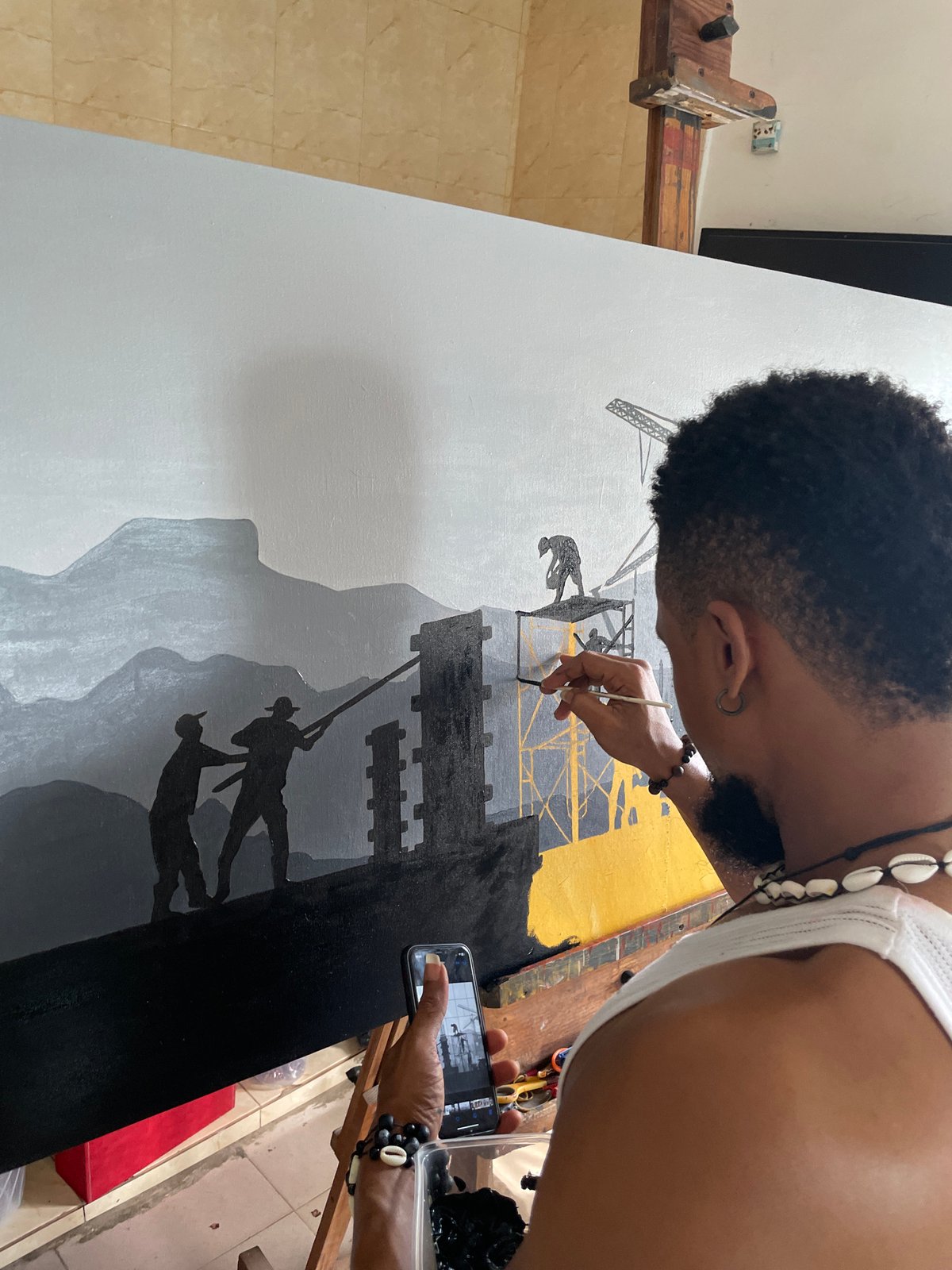 Artist paints mountain landscape with silhouetted figures in Ado