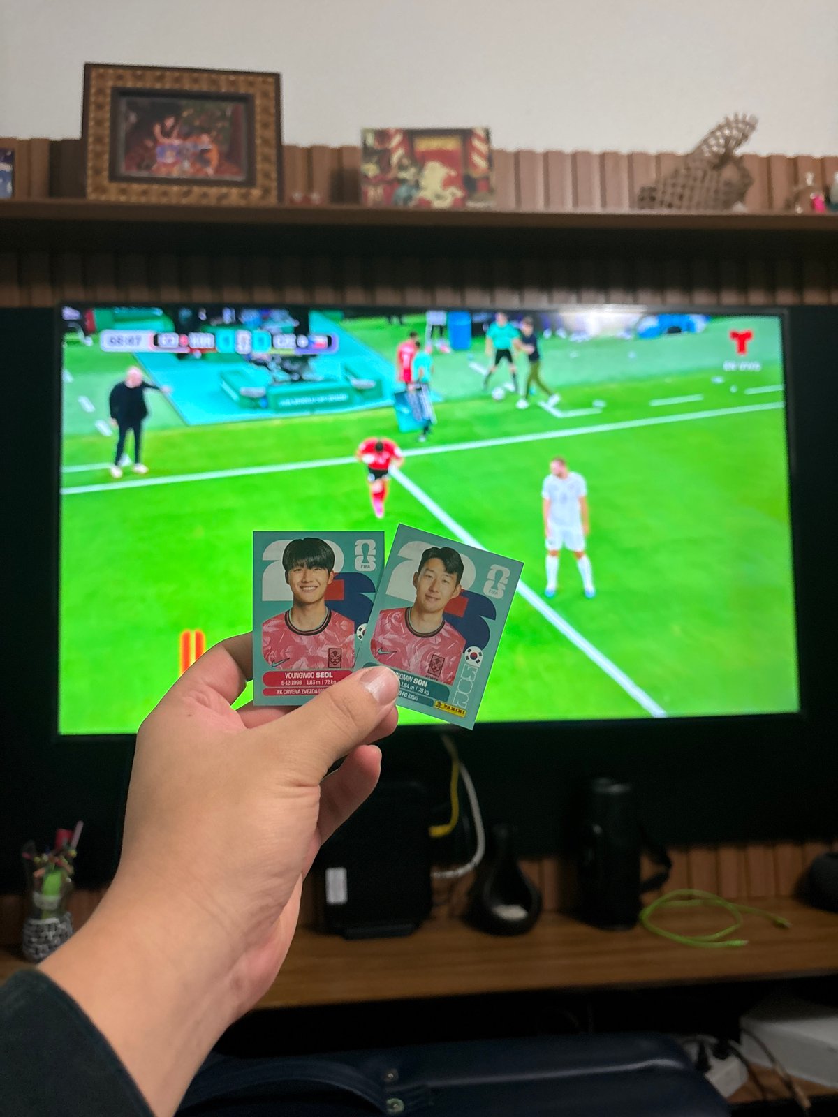 Soccer fan displays Son trading cards during televised match
