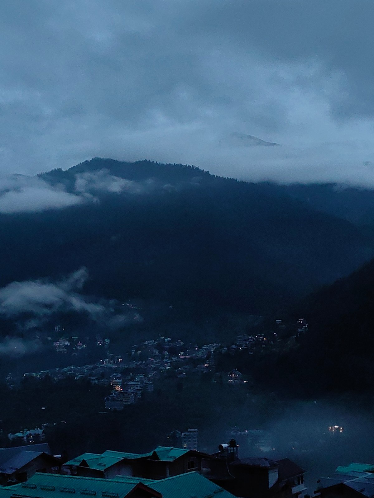 Fog and dusk settle over Vashisht's misty mountain valley