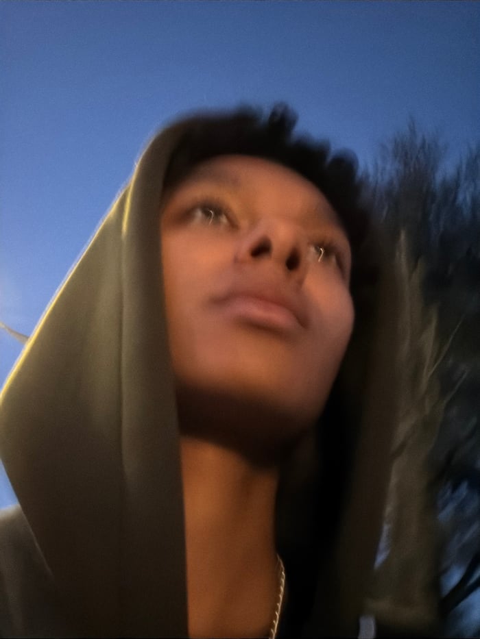 Young person in hoodie photographed against blue sky
