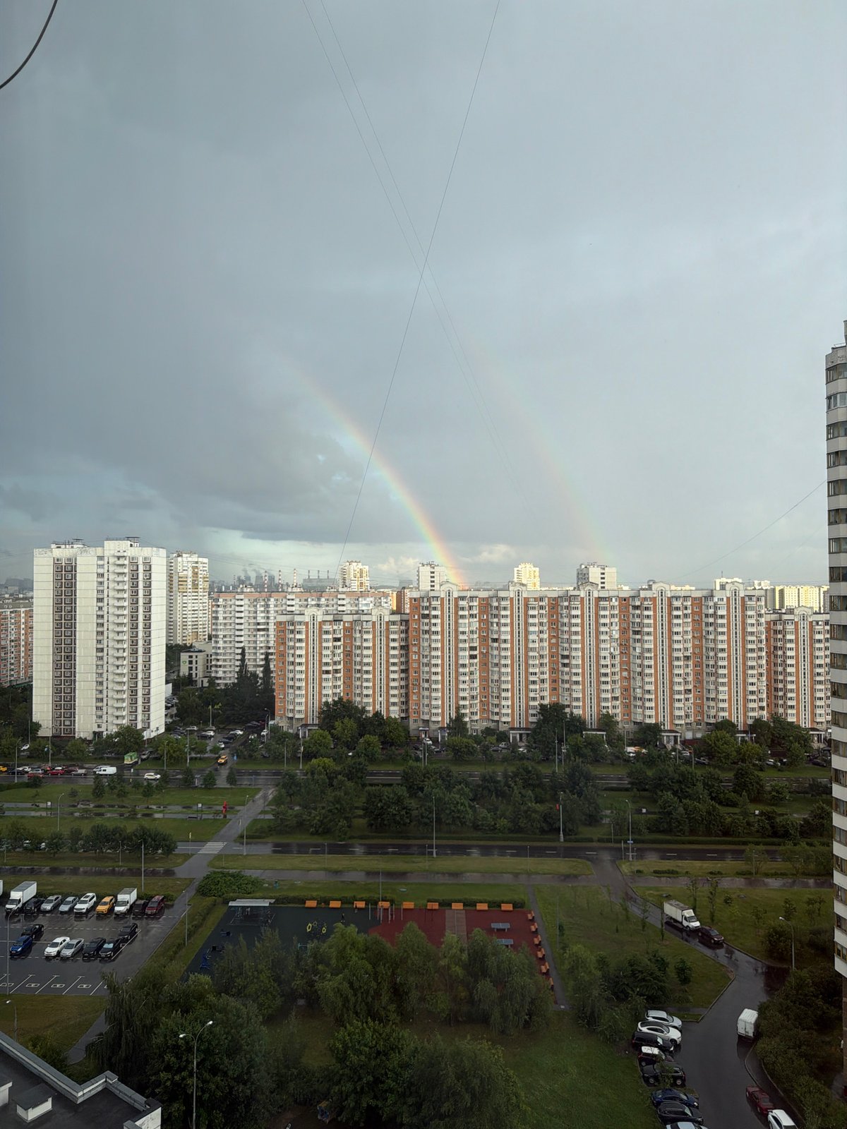 Double rainbow over Moscow apartment blocks, overcast afternoon