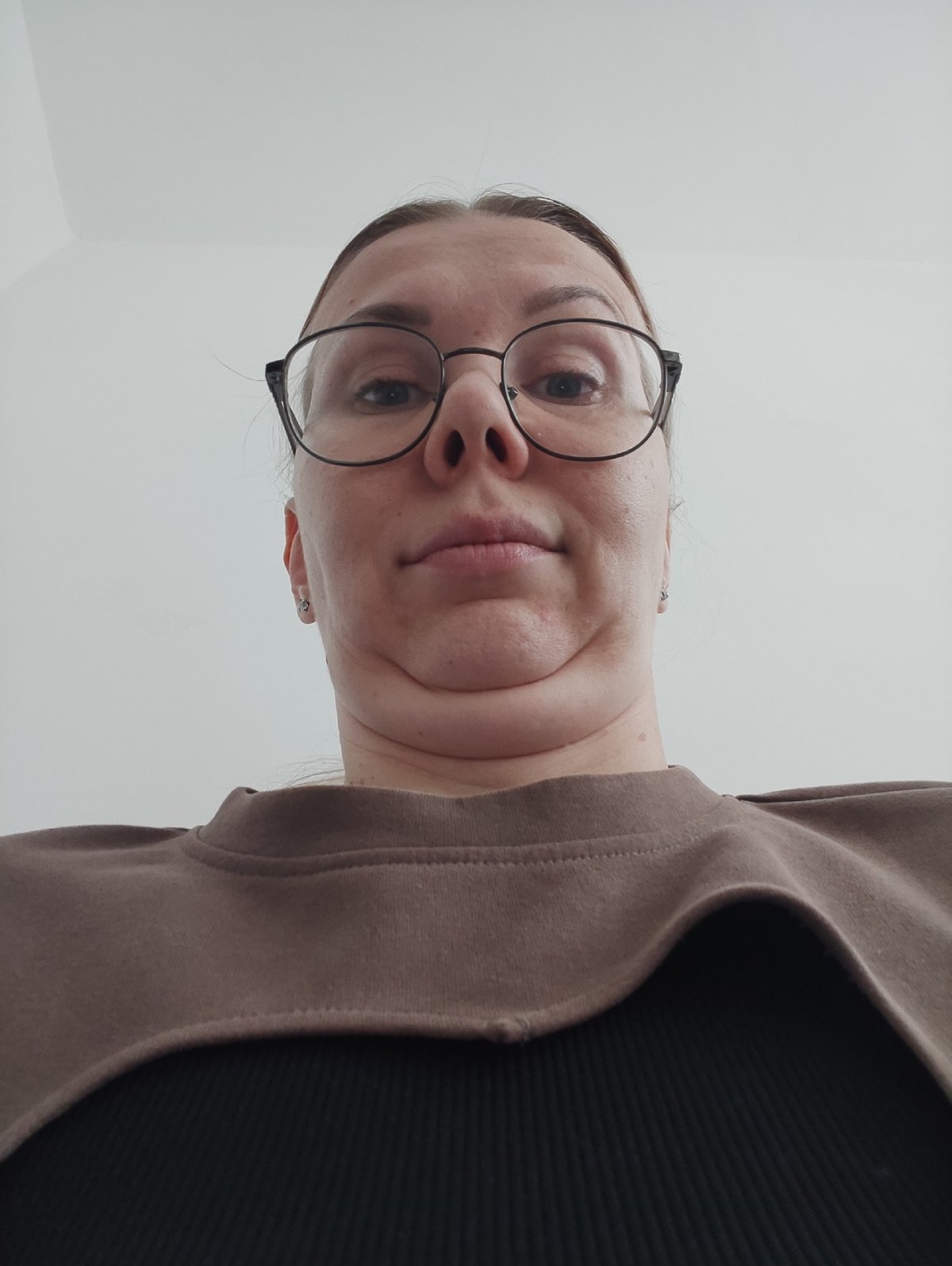 Woman in brown sweatshirt photographed indoors against white background