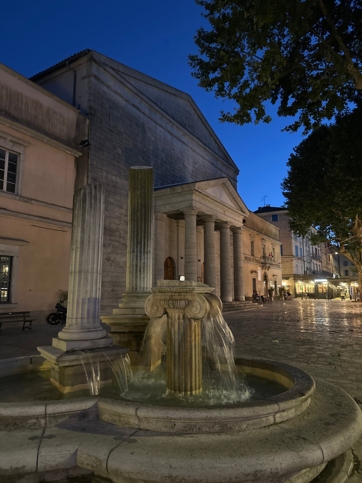 Anduze at twilight: fountain, clock tower, and lit streets