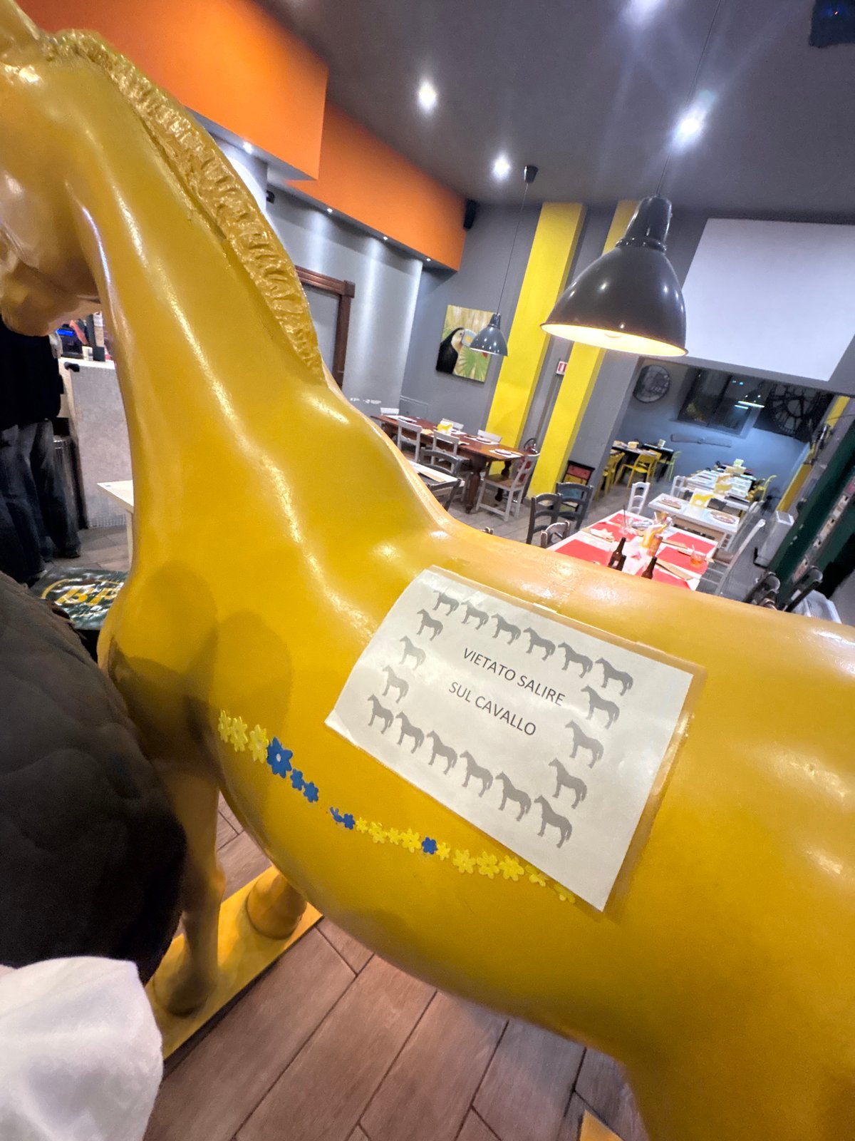 Women pose with yellow horse sculpture in Milan cafe