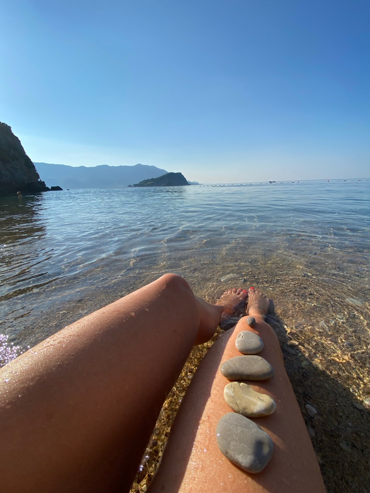 A slow morning along the Budva waterfront, beach to clifftops.