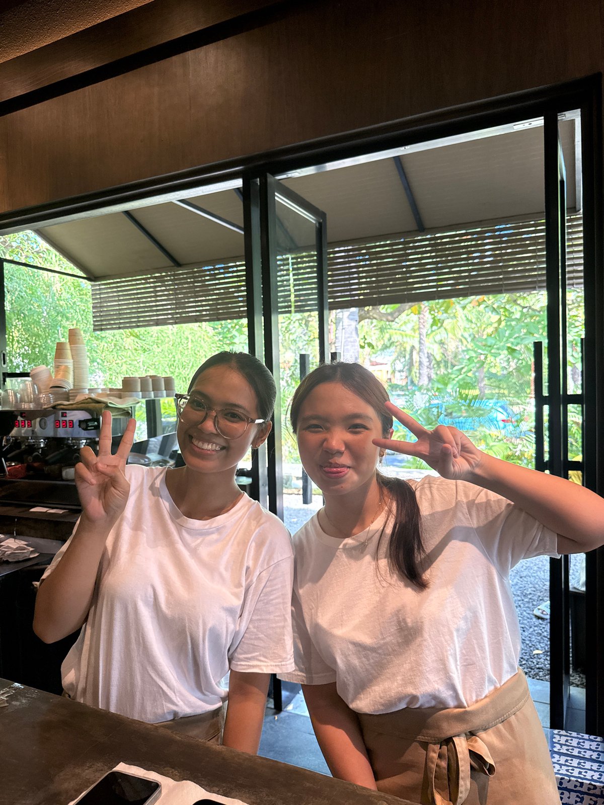 Young women pose at Kuta Selatan cafe with friendly barista