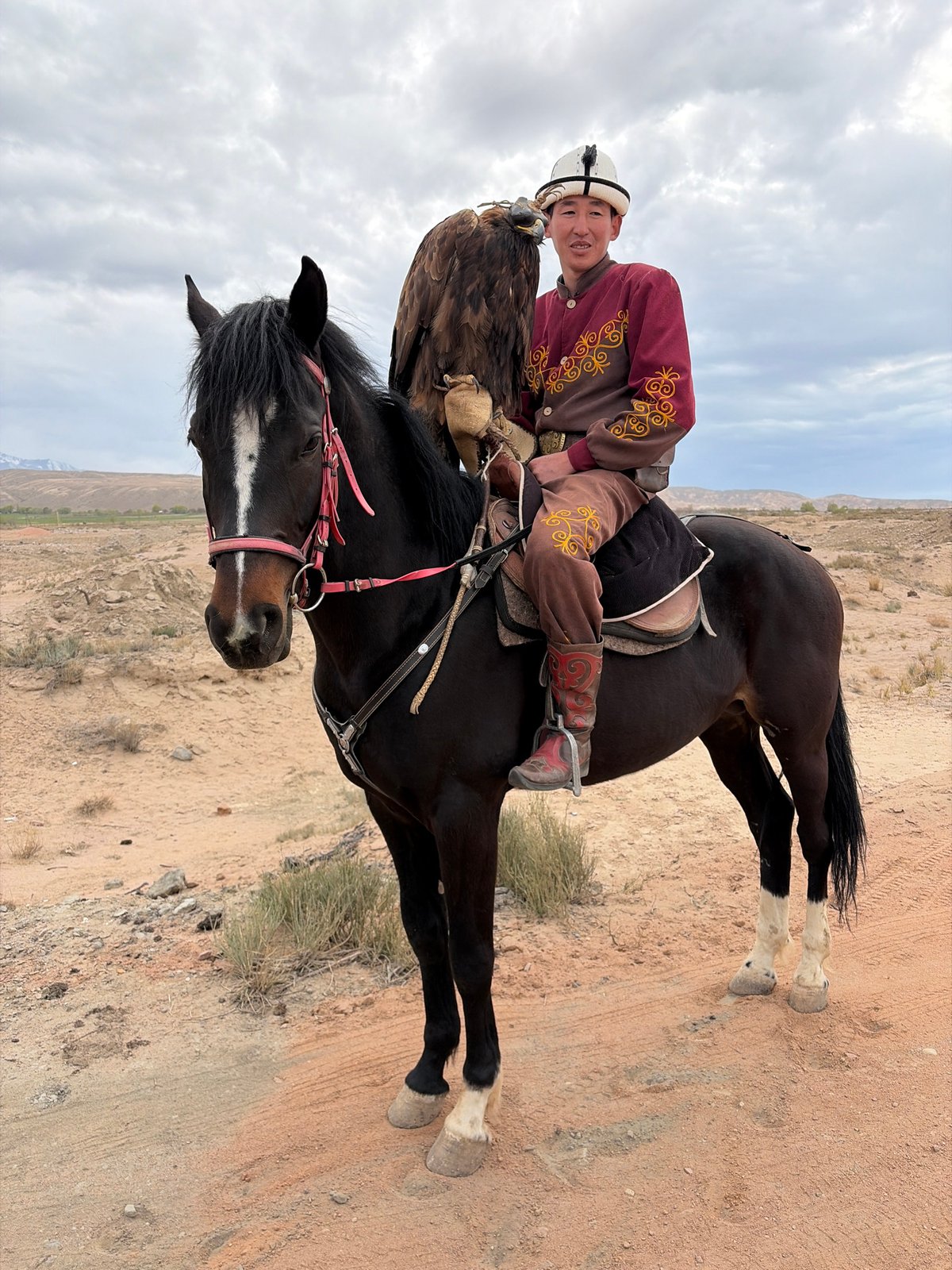 Eagle hunter poses with bird on horseback in Kyrgyzstan