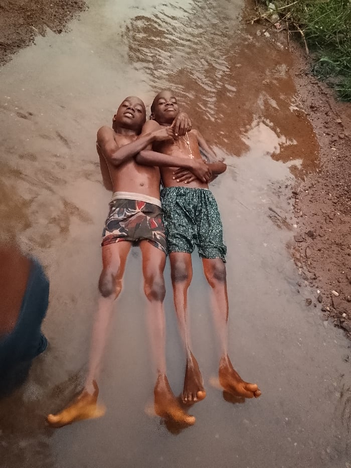 Children play and bathe in muddy puddles in Nigeria