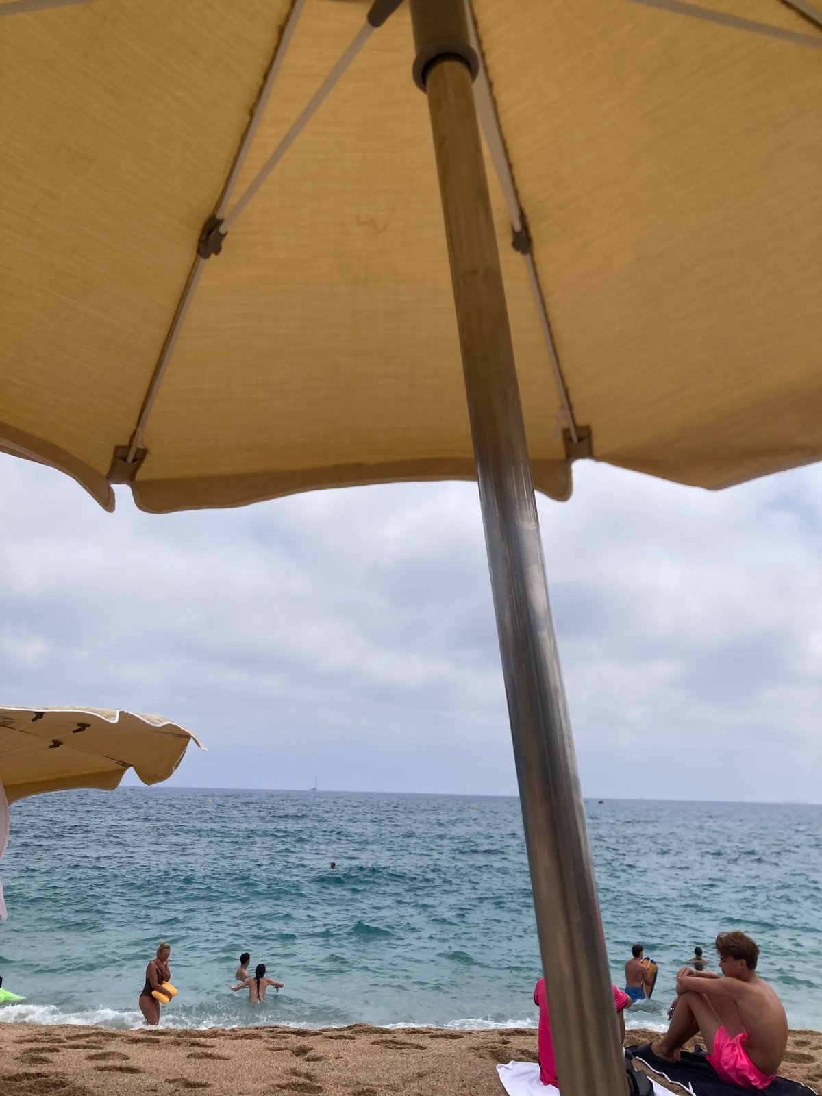 Crowded beach day in Lloret de Mar with parasailing overhead