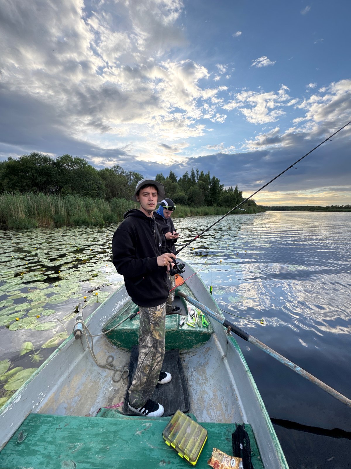Fishing from a metal boat among reeds on calm Saint Petersburg waters.