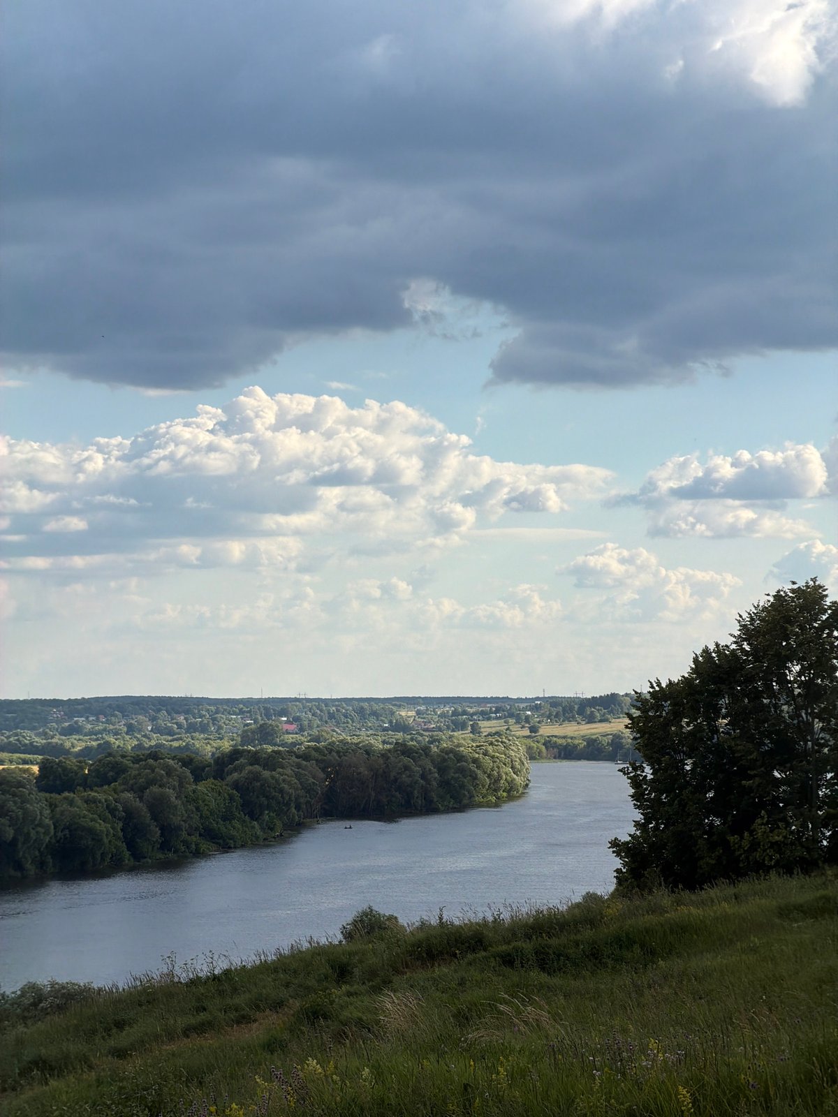 A quiet river landscape with passing boat and rolling green hills
