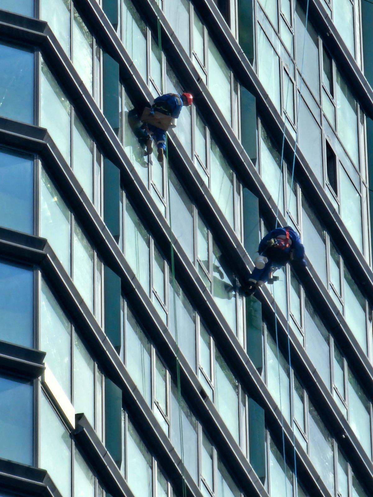 Window cleaners work Moscow high-rises as pedestrians navigate city