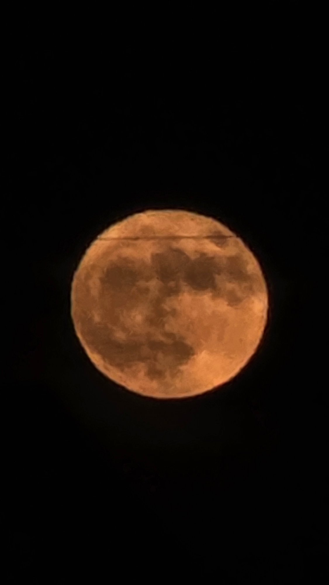 Full orange moon observed partially obscured by power lines
