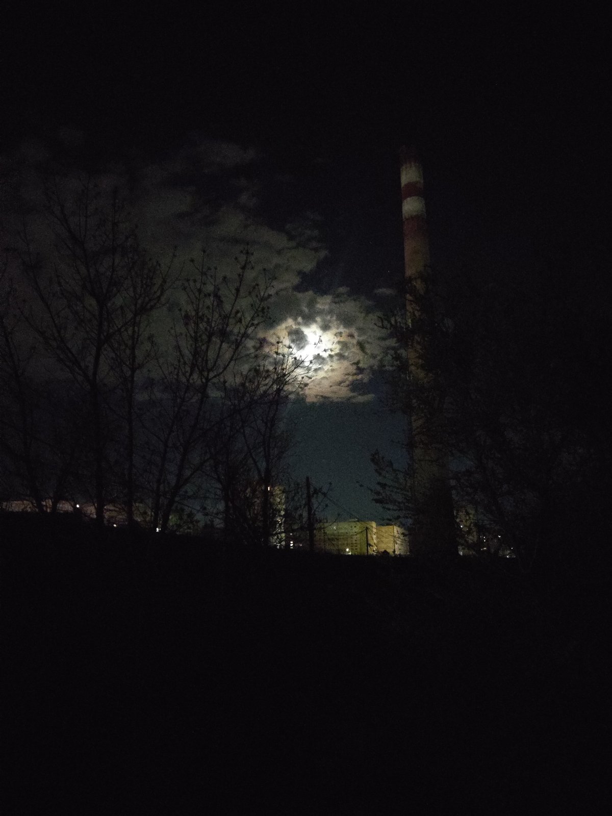 Moonlit industrial chimney observed against cloudy Yerevan sky