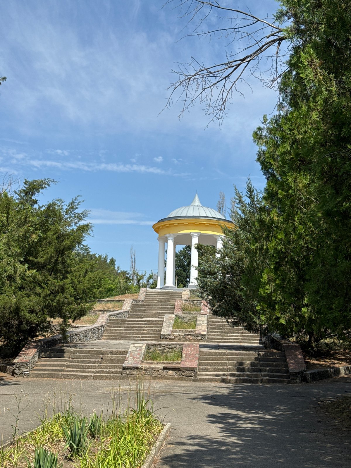 White gazebo crowns a tree-lined stone staircase