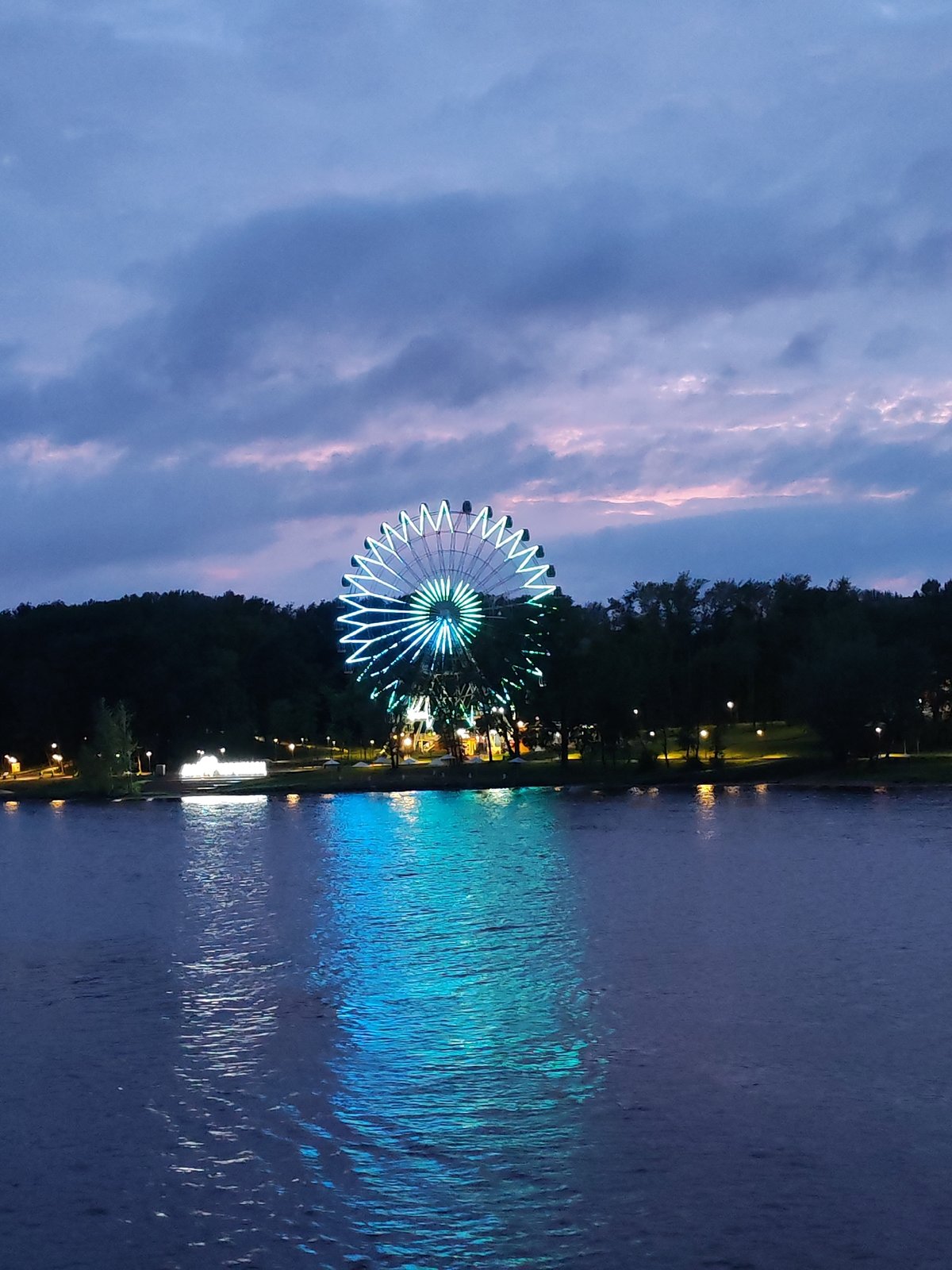 Ferris wheel lights up Cherepovets waterfront at dusk