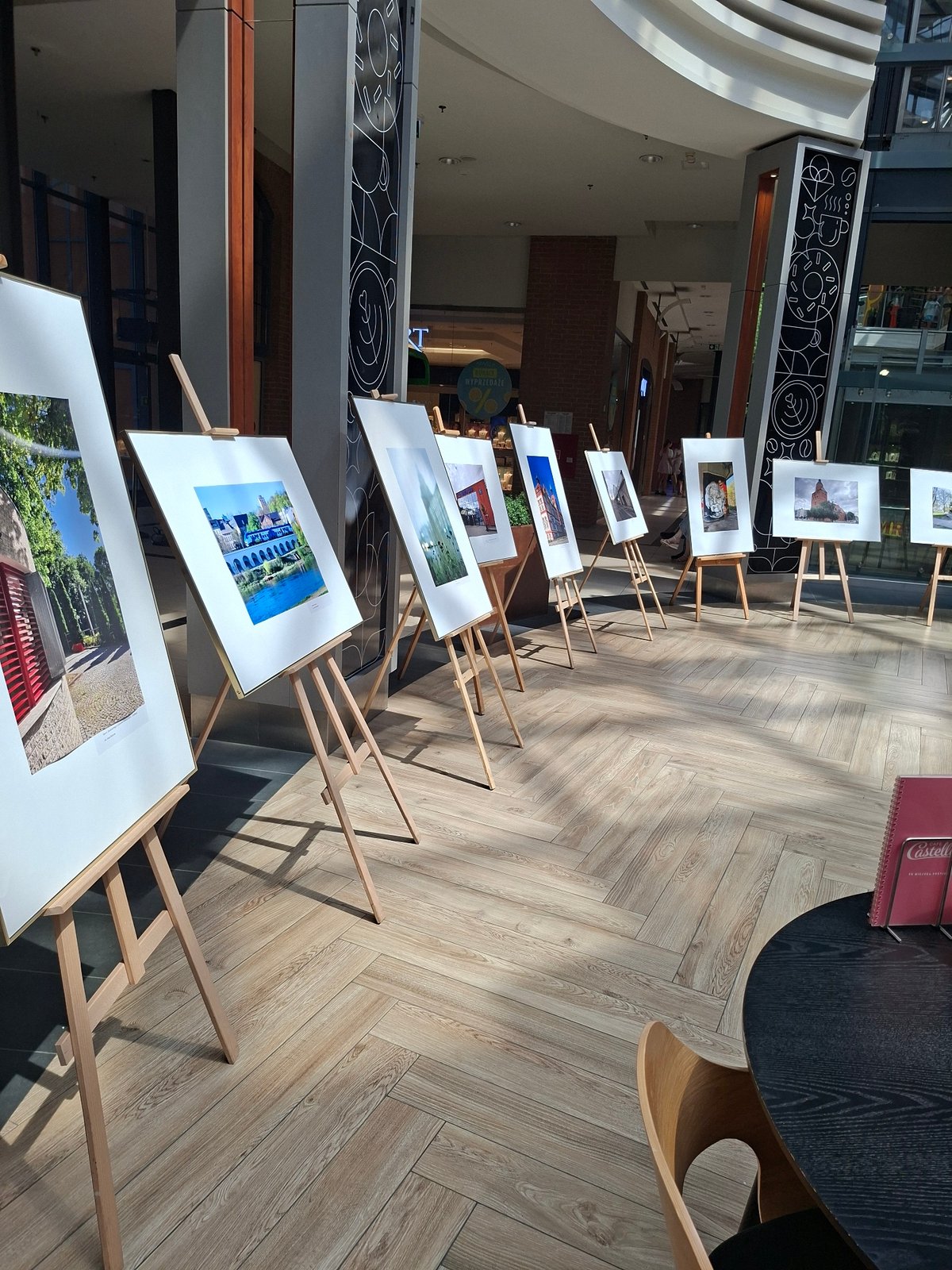 Browsing a mall photo exhibition with escalators and atrium in view