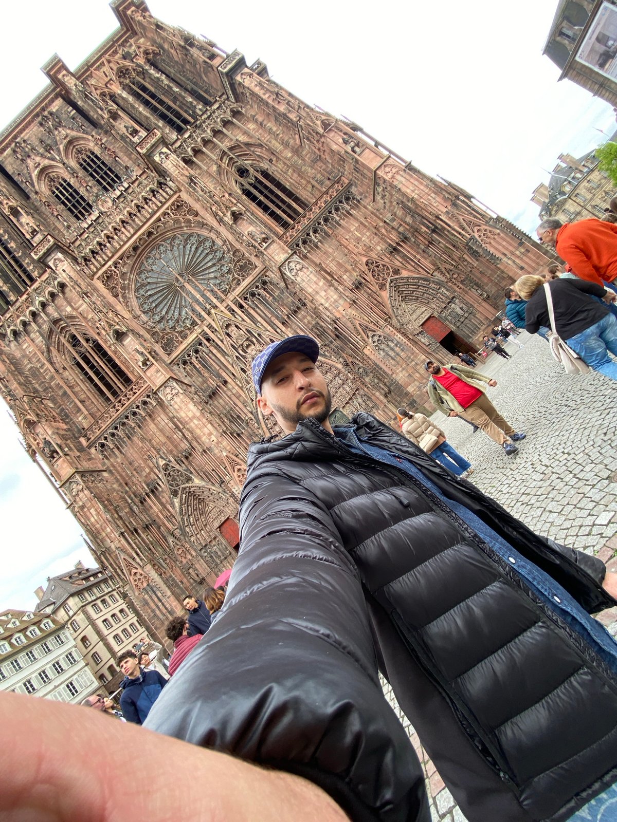 Tourist poses at Strasbourg Cathedral amid afternoon crowd