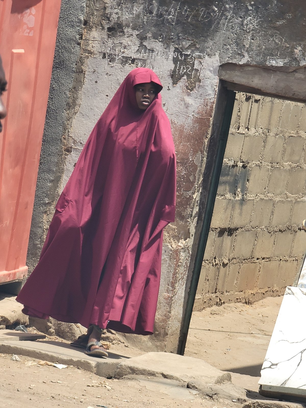 Person photographed against weathered walls in Maiburiji, Nigeria
