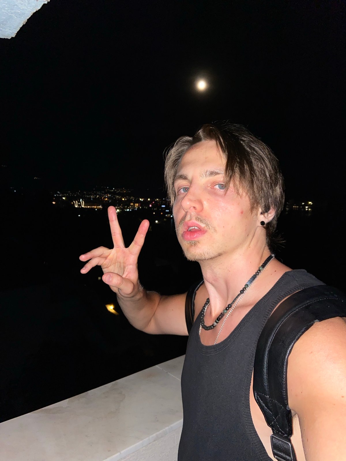 Young man poses on ledge during moonlit night in Šušanj