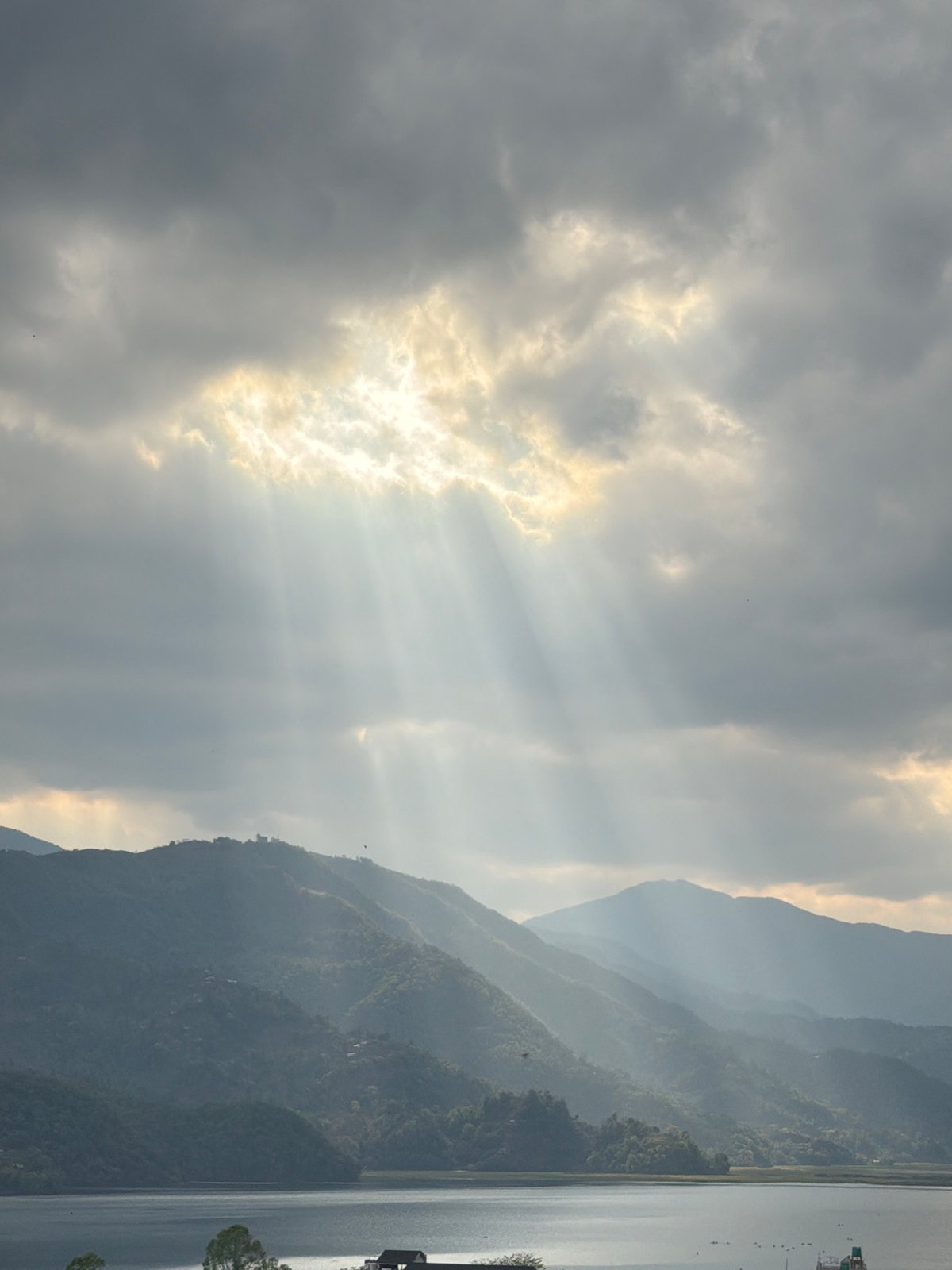 Sunbeams pierce clouds over Pokhara's mountain landscape