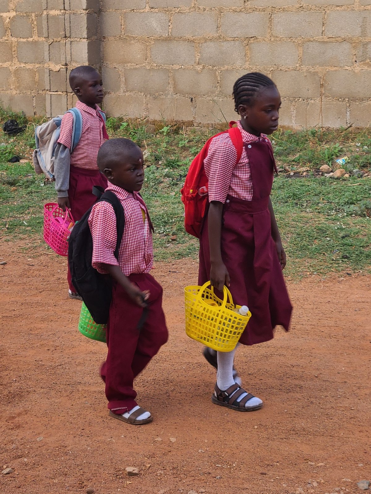 School children walk dirt roads during morning commute in Nigeria