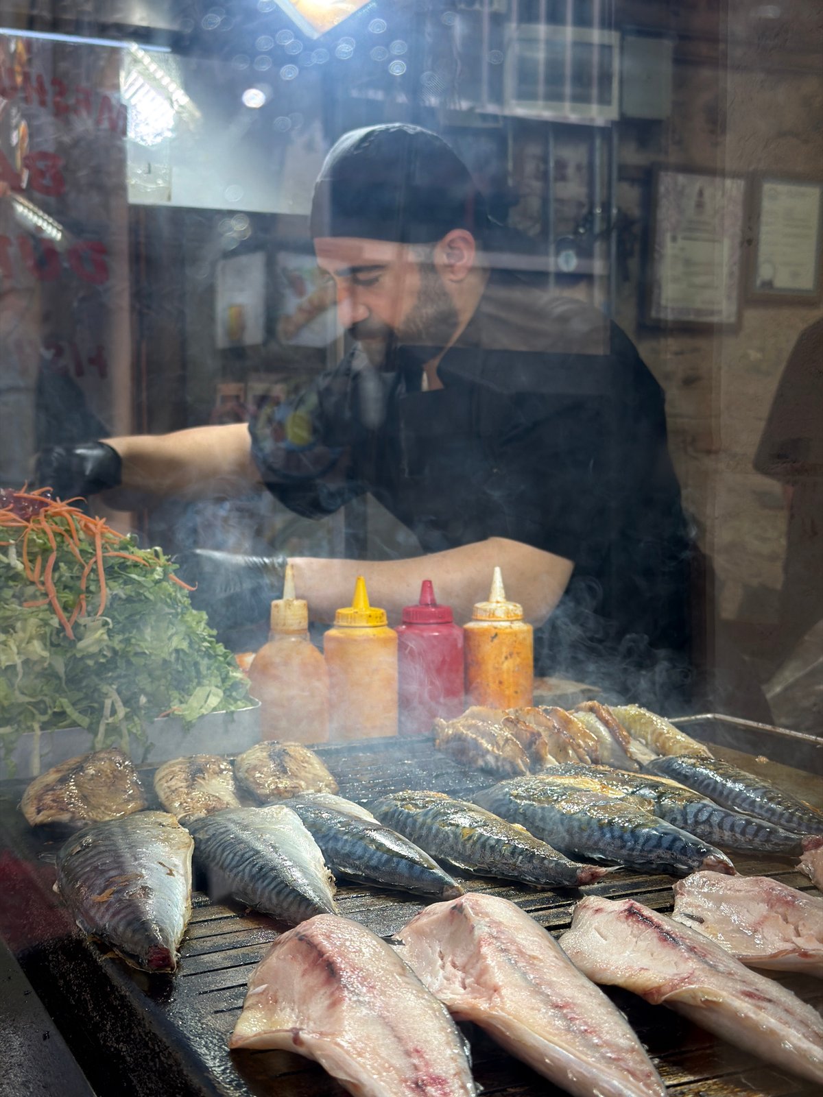Fish vendor prepares meal at glass stall in Beyoğlu