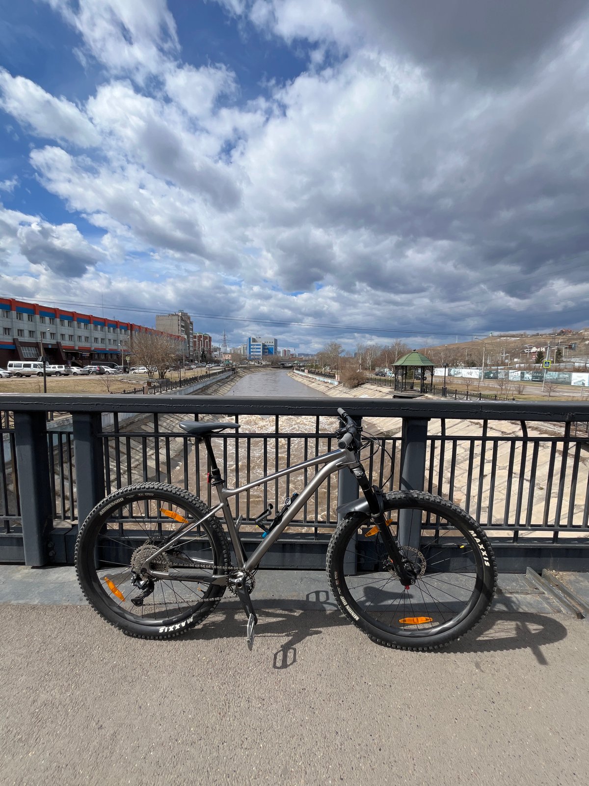 Early morning cyclist pauses on Krasnoyarsk bridge overlooking muddy river
