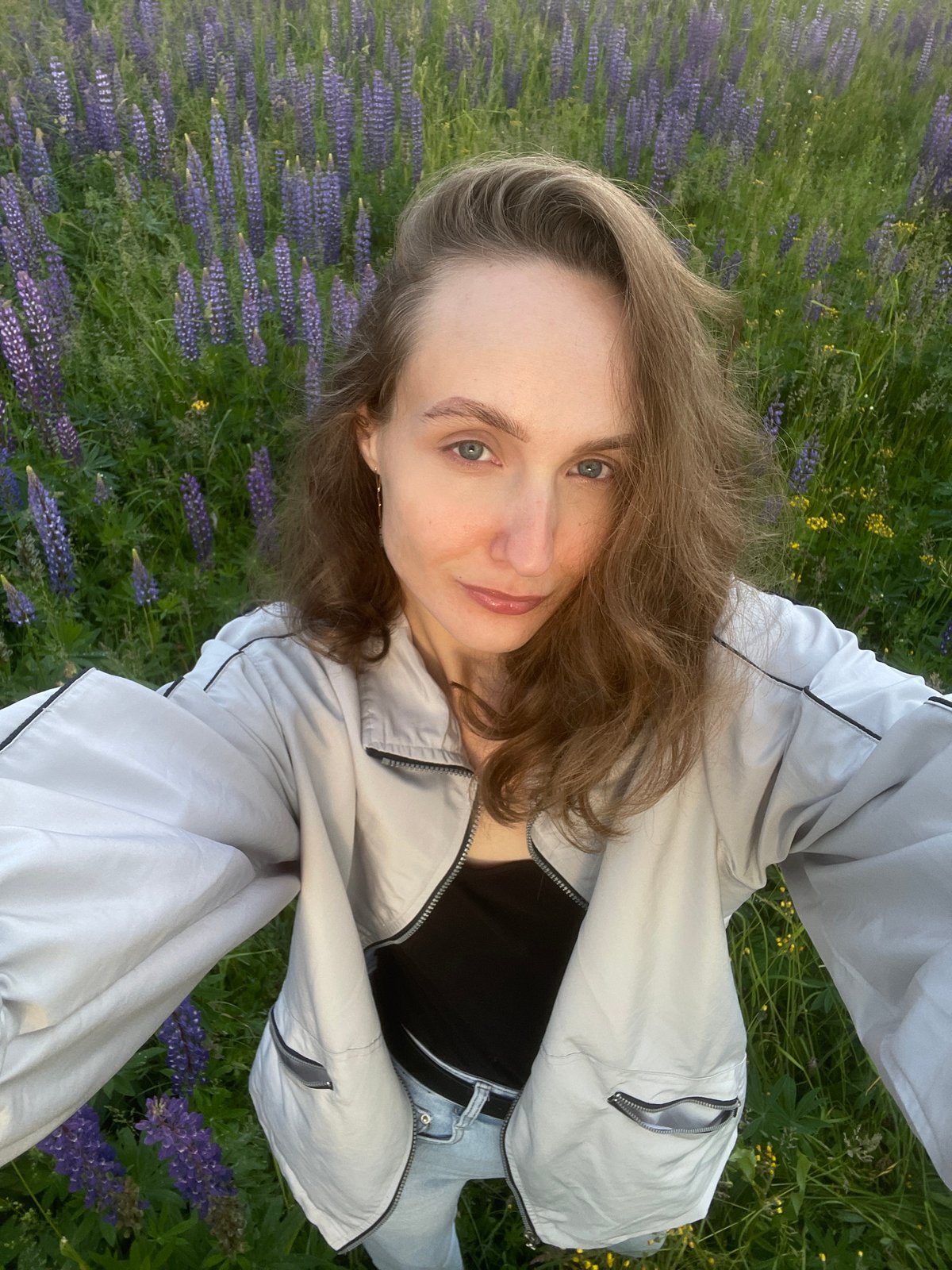 Woman photographs lupine flower picking session in Russian countryside