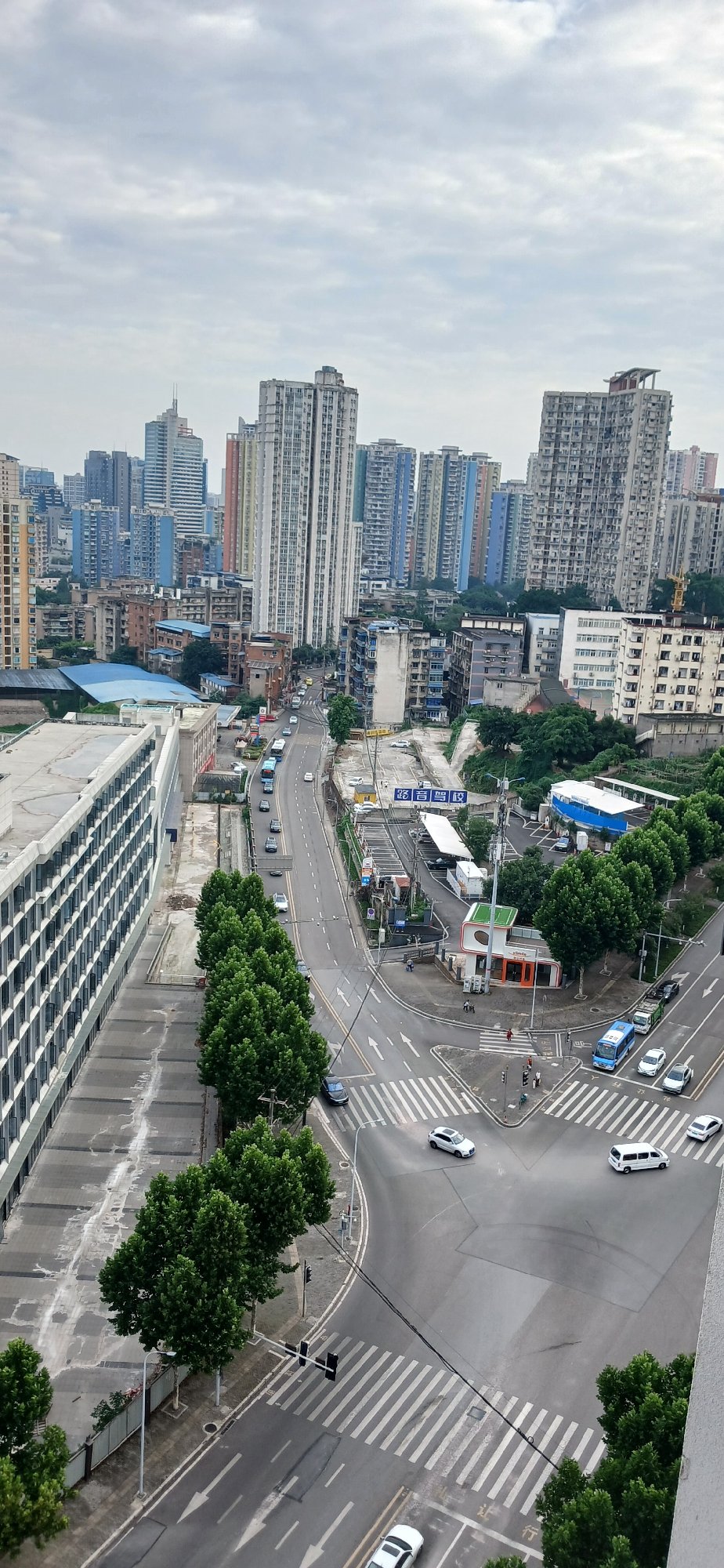 Overcast day at busy Jiulongpo intersection with airplane overhead