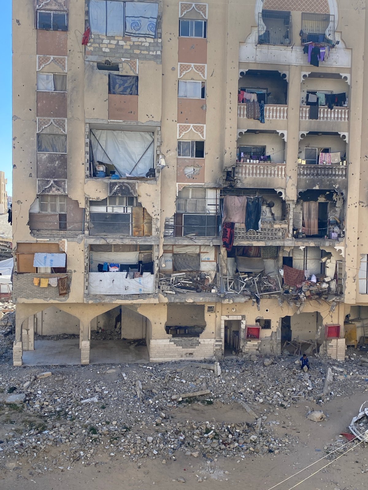 Damaged apartment building documented near debris-strewn street