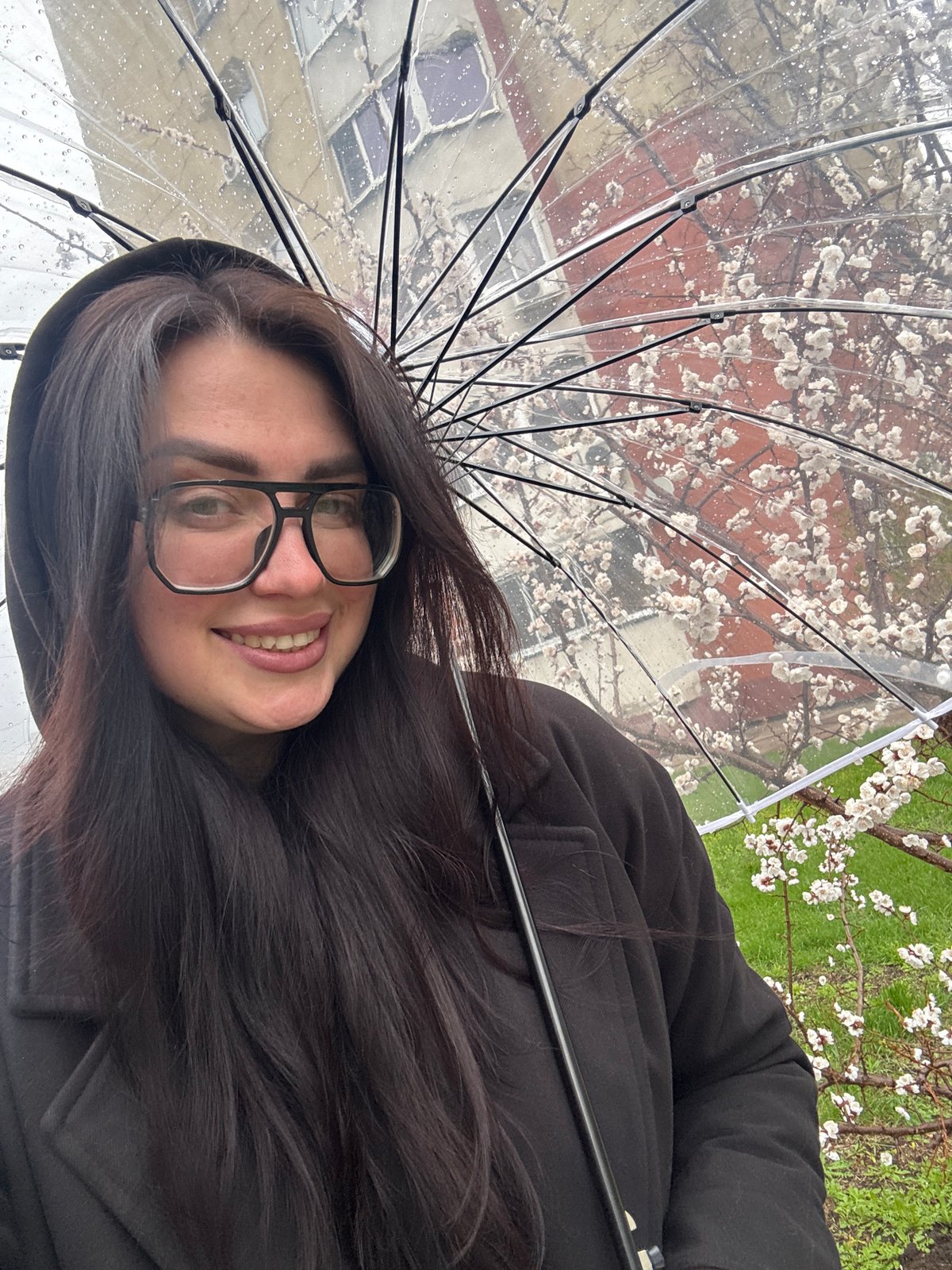 Woman shelters under clear umbrella during urban rainfall