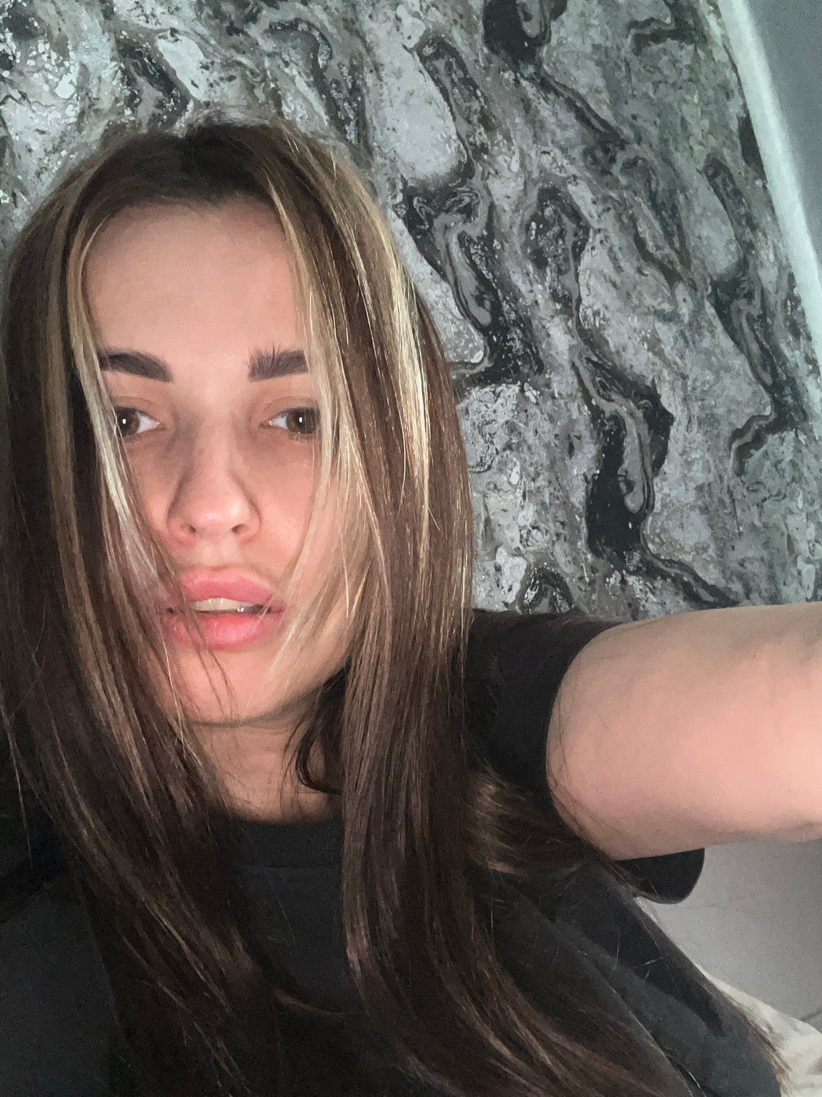 Woman takes multiple selfies on marbled surface during evening session