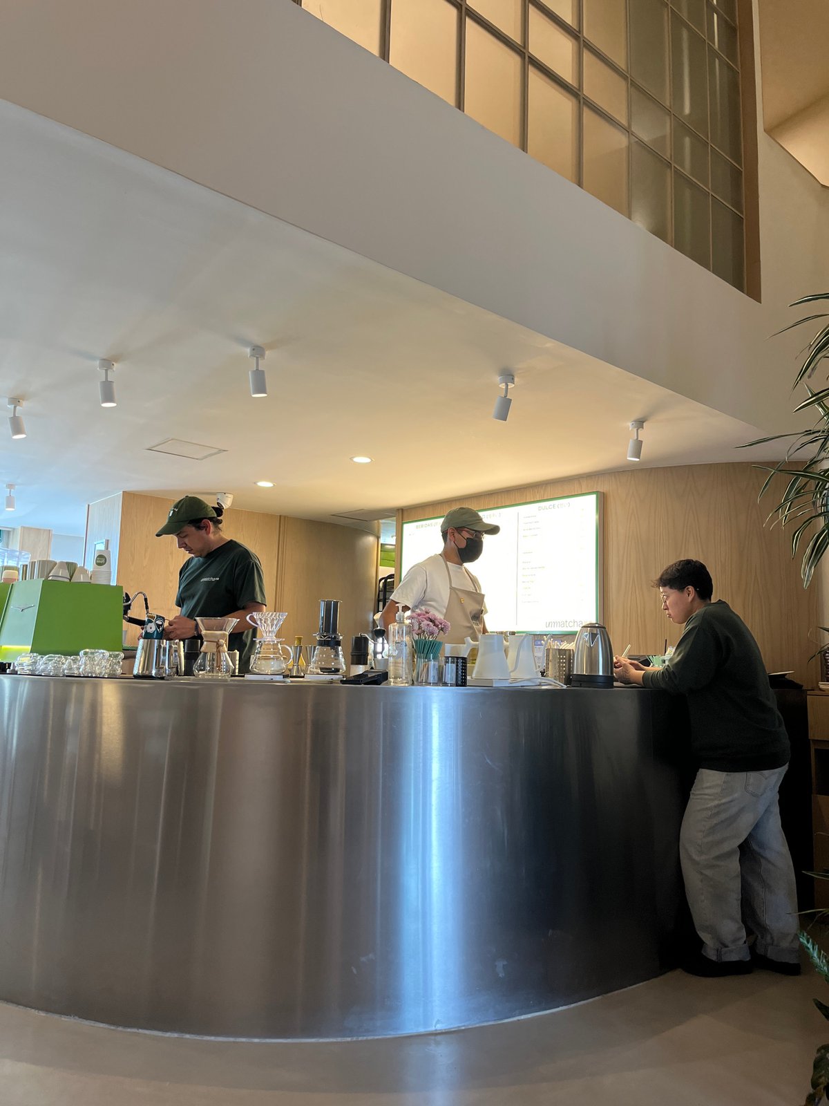 Three people behind steel counter at unknown business