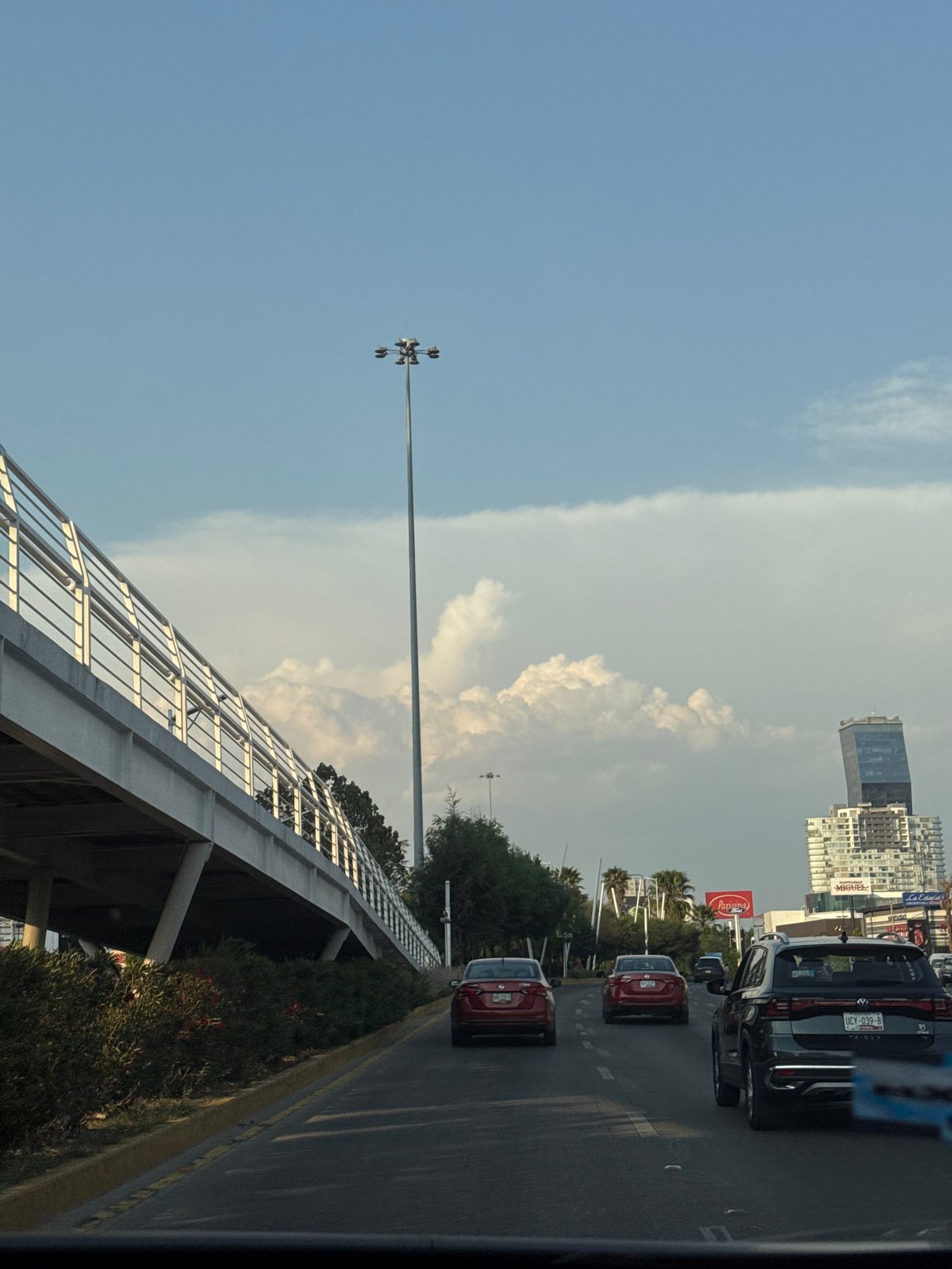 Traffic flows through Puebla streets near Coca-Cola billboard