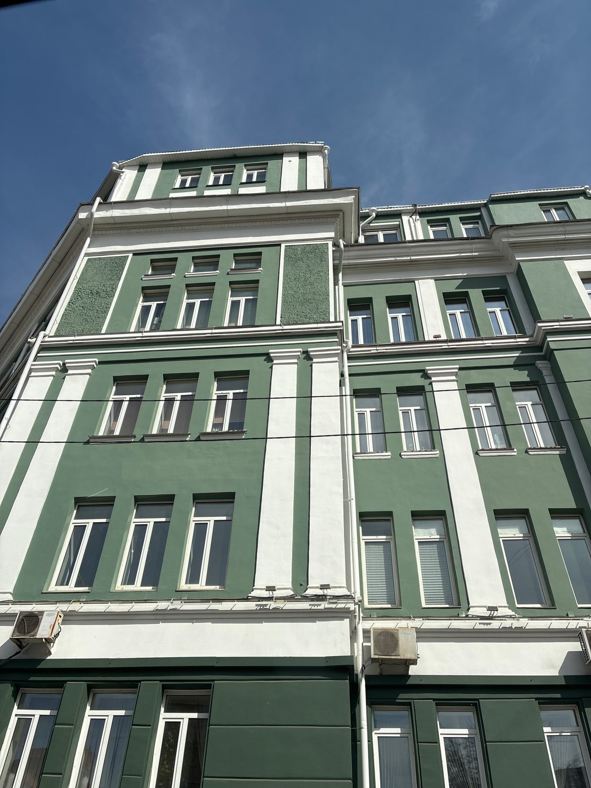 Green and white building with vertical wiring documented
