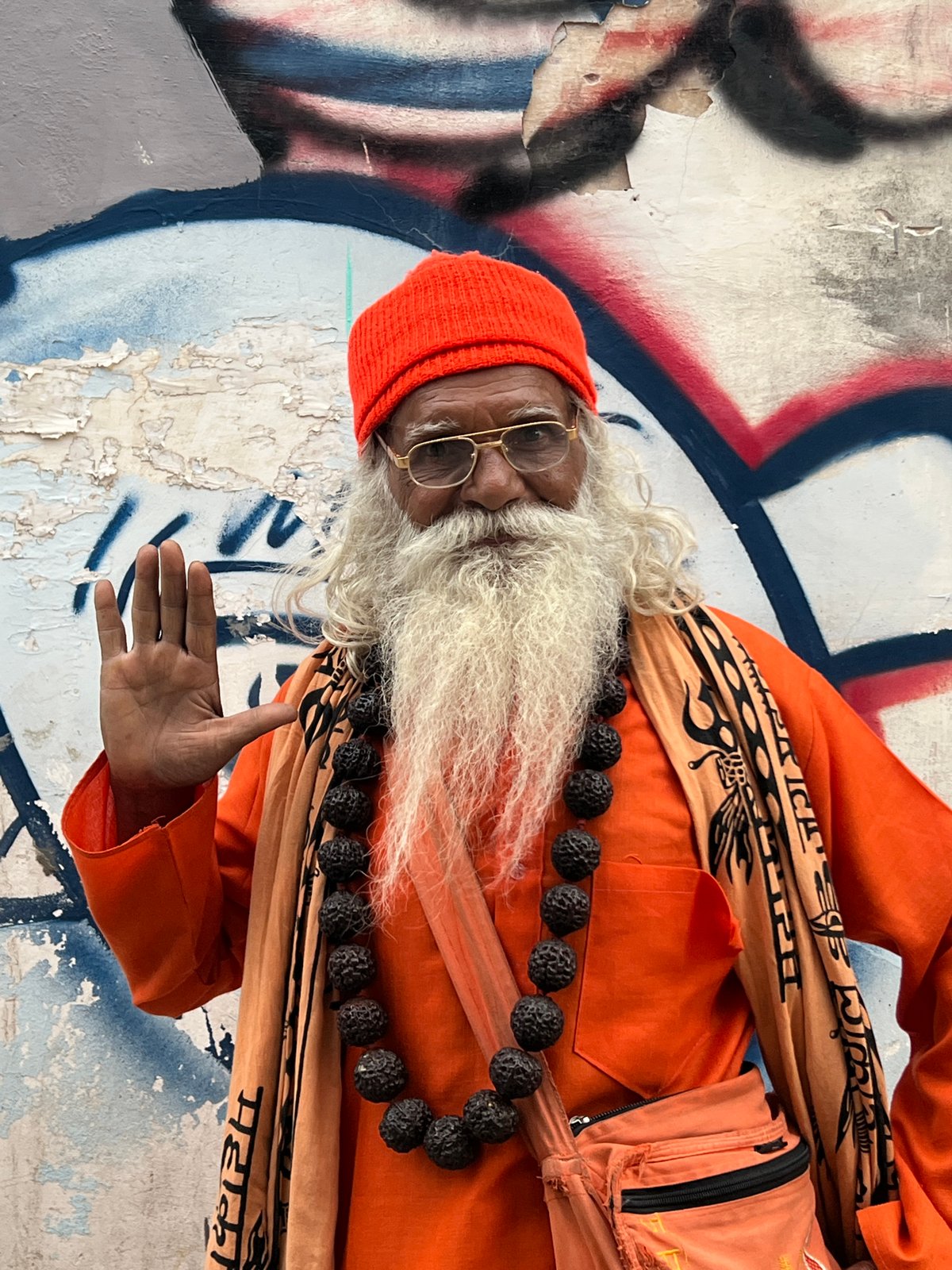 Orange-robed figure by a graffiti wall in Pushkar