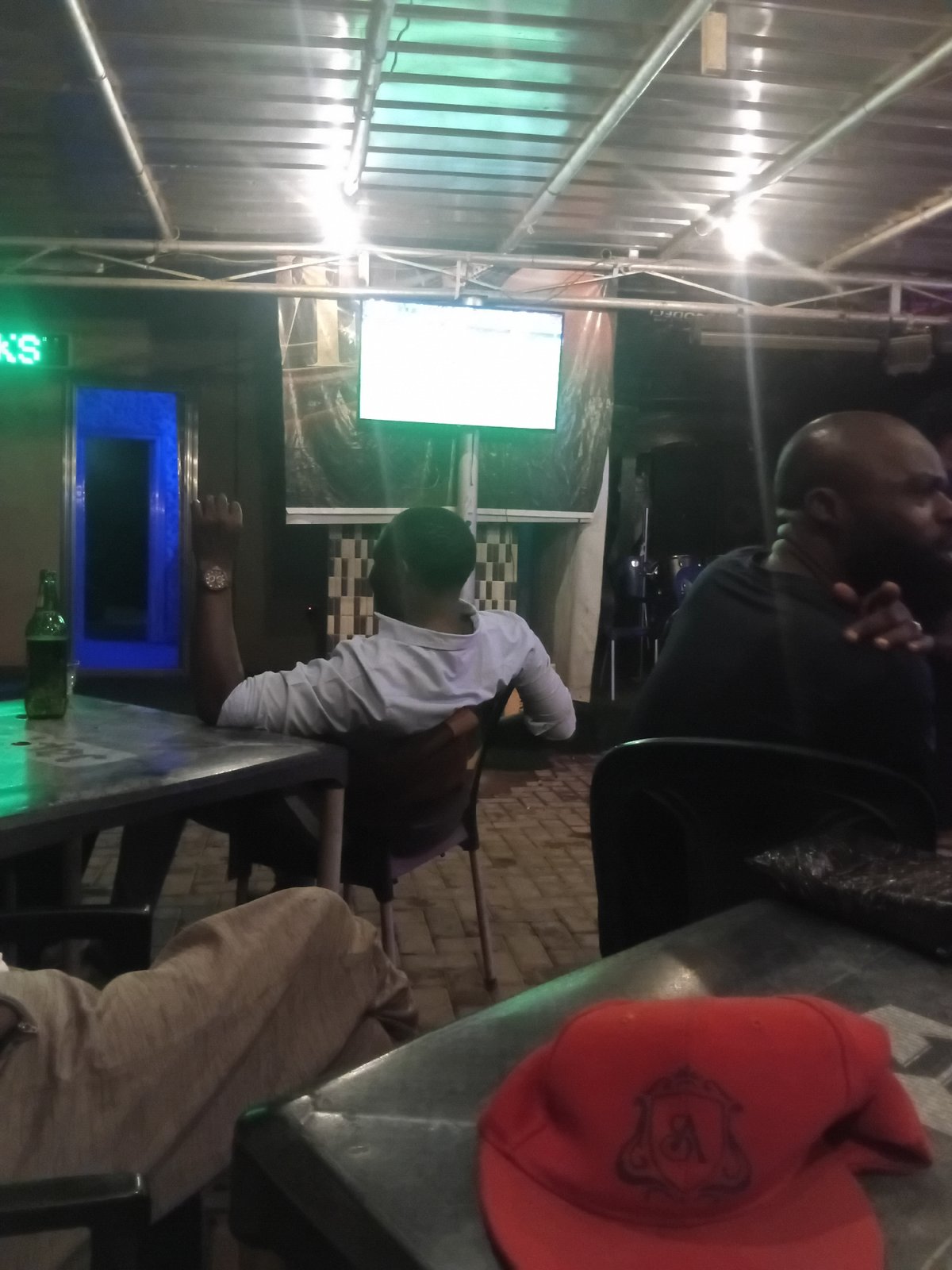 Evening gathering documented at Nigeria bar, red cap observed