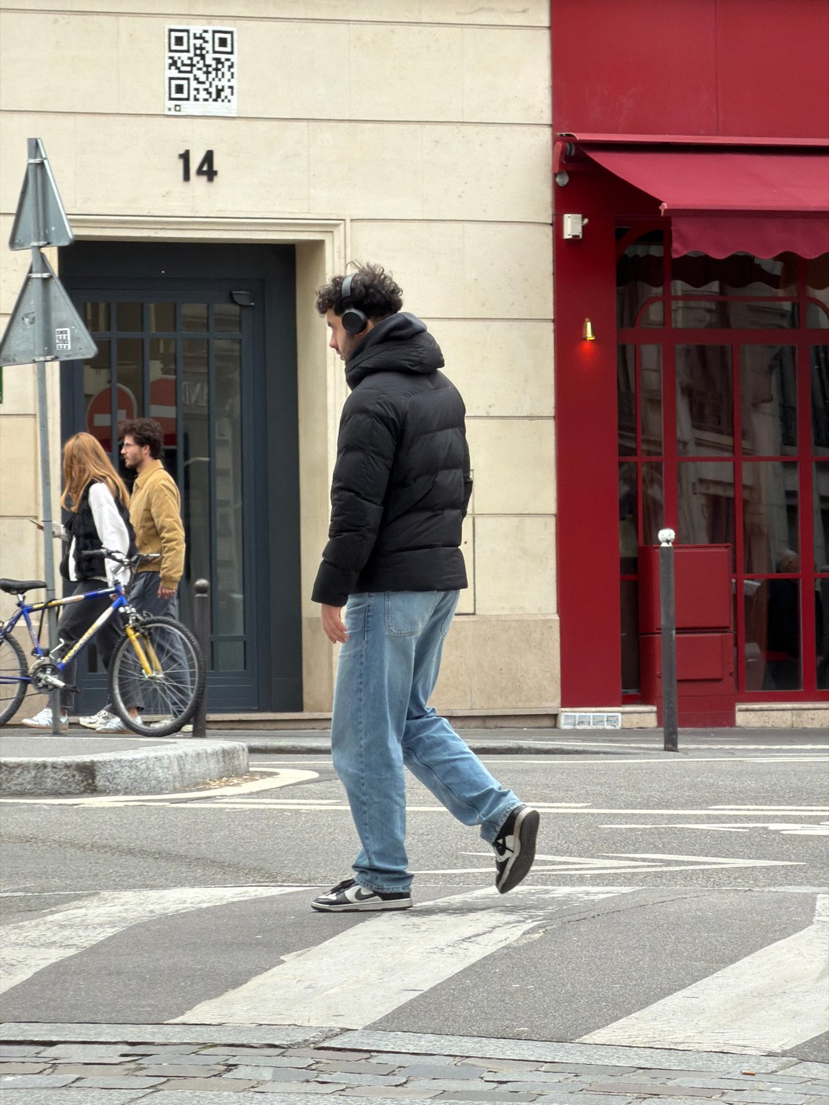 Man in headphones walks Paris sidewalk Friday morning