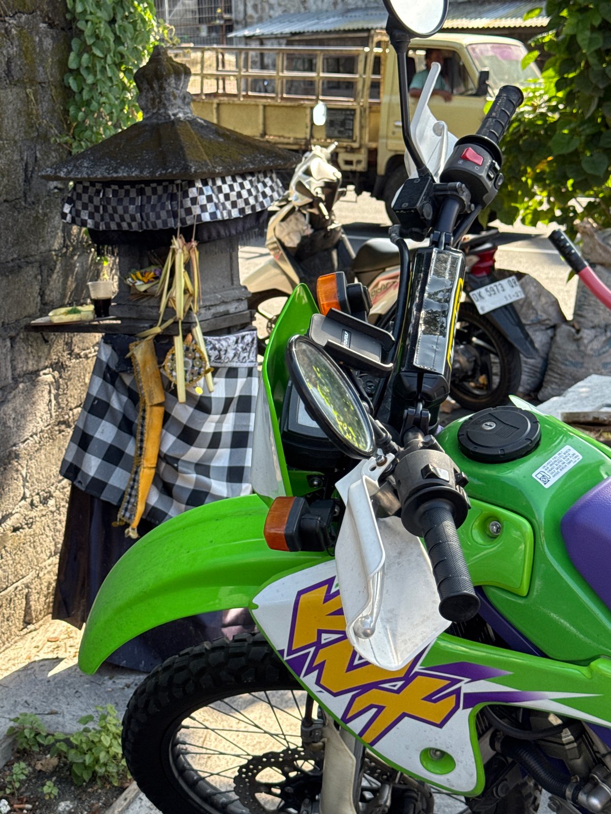 Indonesian coconut vendor prepares fresh coconuts near decorated motorcycle