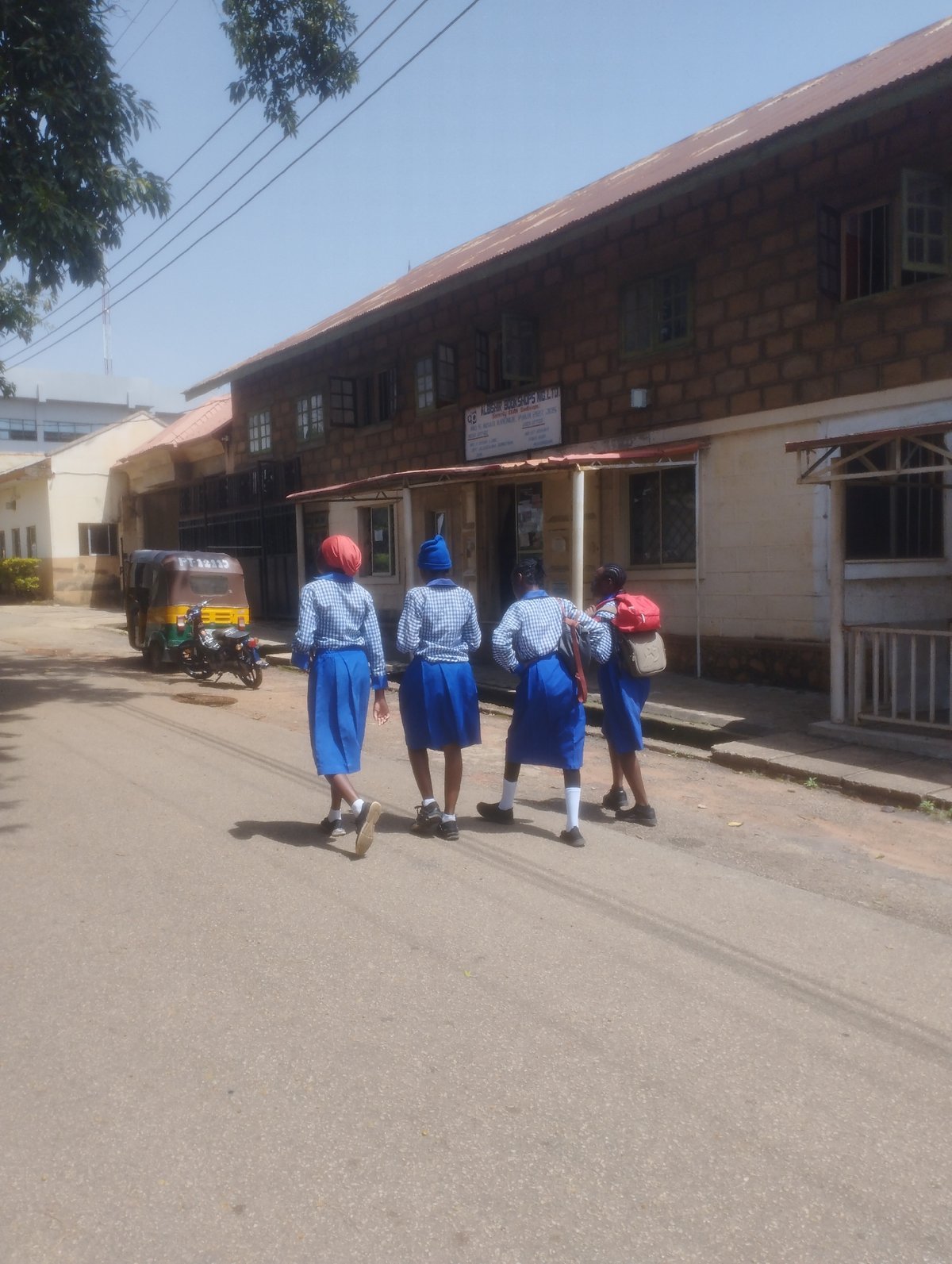 Midday street life in Jos: students, vendors, and city traffic