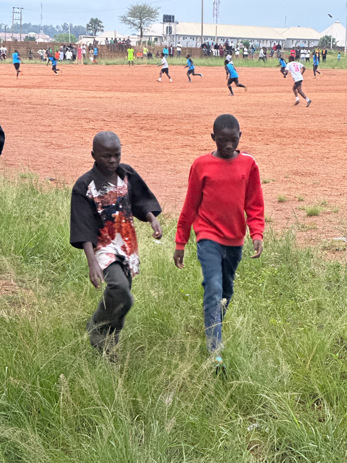 Community soccer match on dirt field in Du, Nigeria
