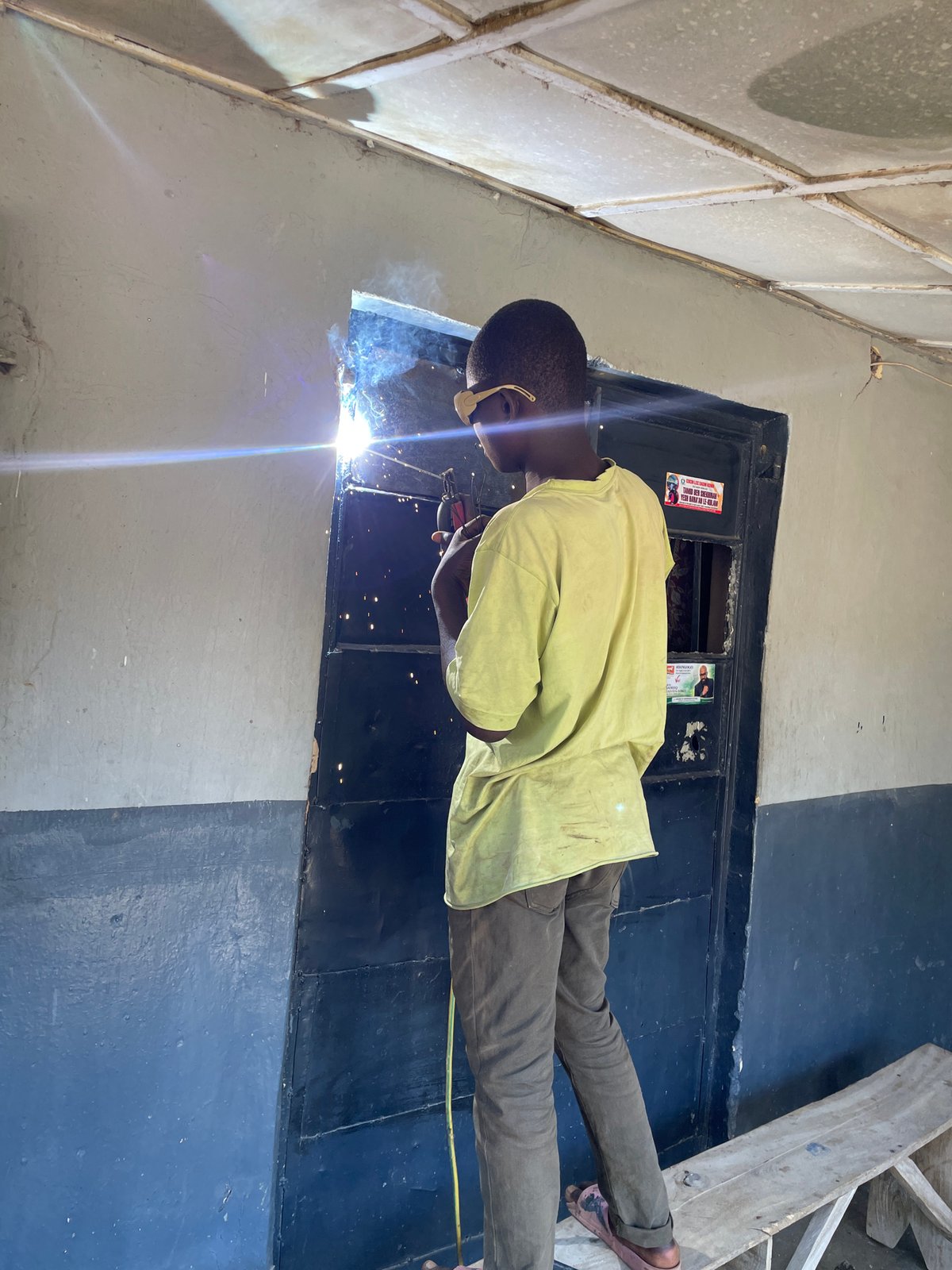 Welder works on metal frames in Jos, Nigeria morning
