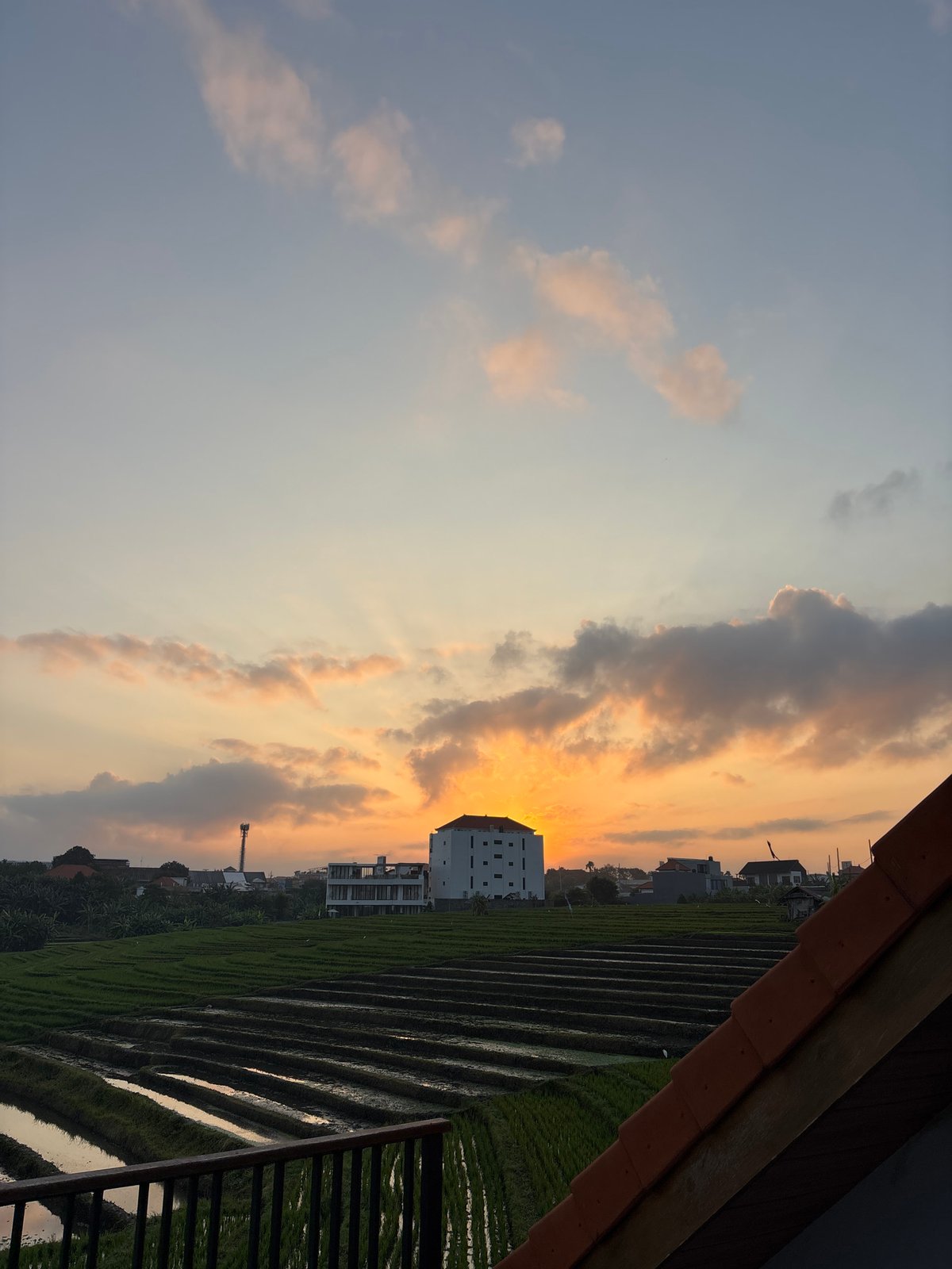 Sunset over rice terraces and a villa pool in North Kuta