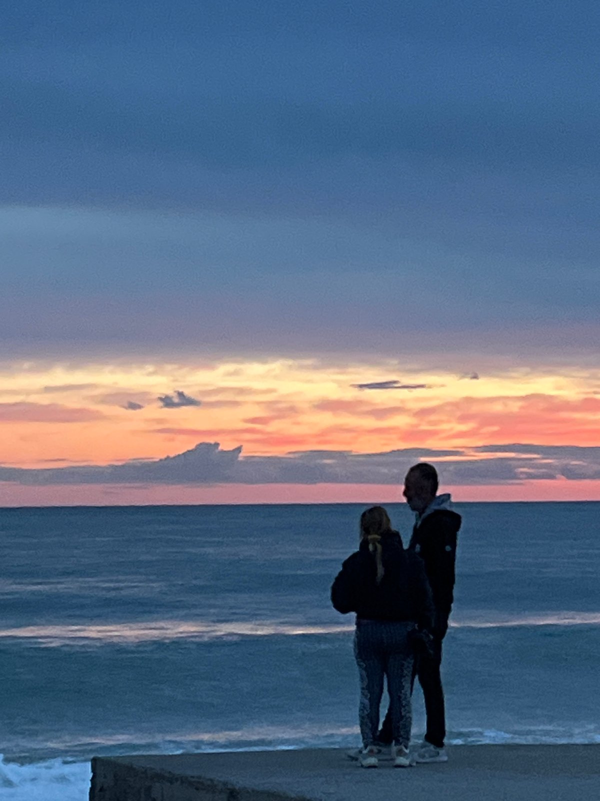 Adult and child watch sunset on Alanya beach