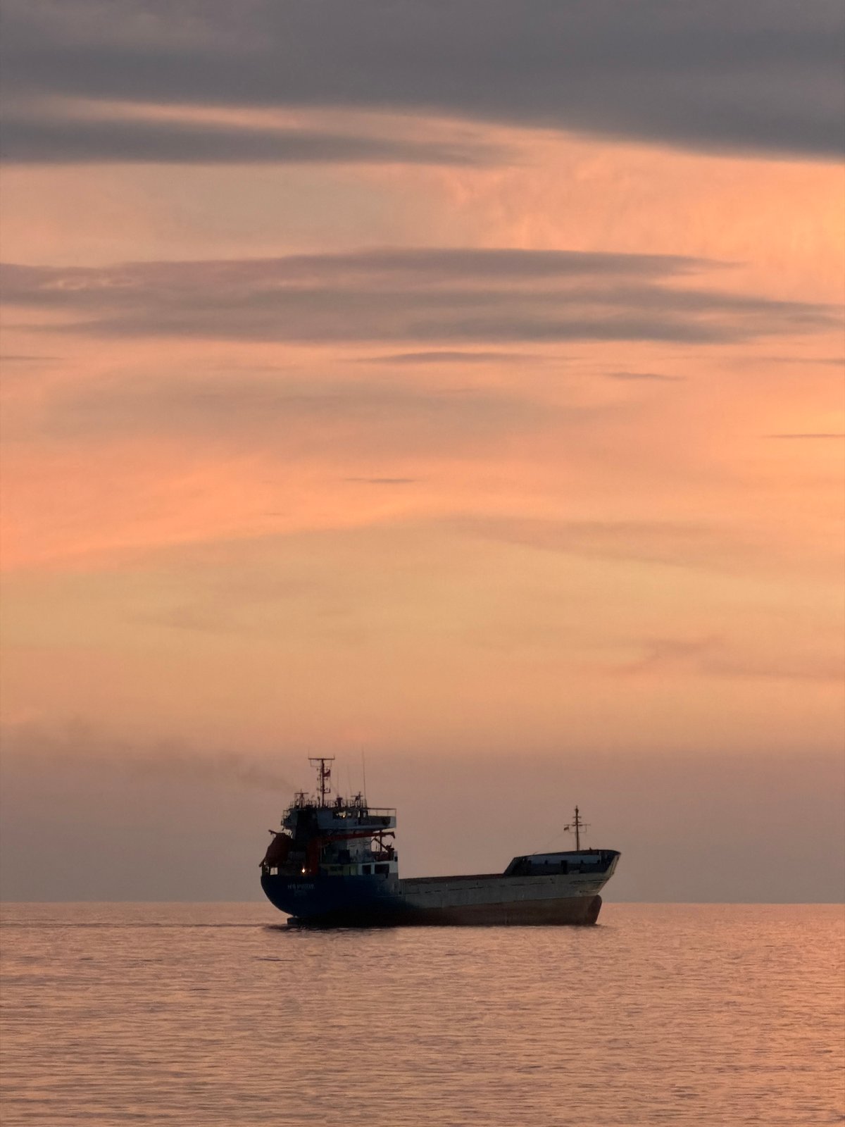 Cargo ship and sailboat silhouetted at dusk off Bar, Montenegro