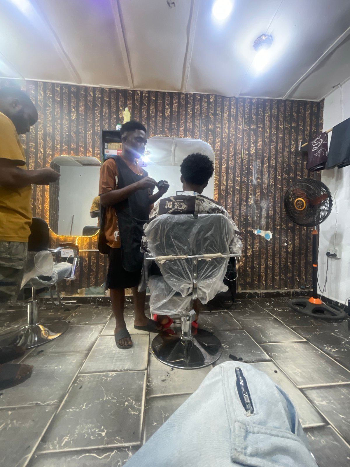 Barber serves customer at Lokoja shop